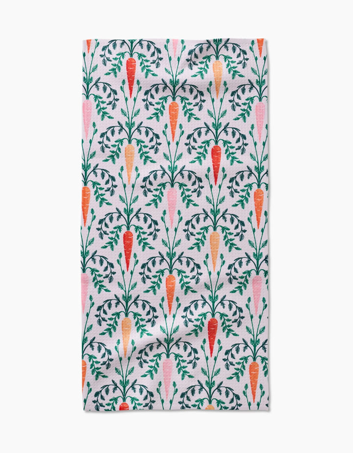 The Carrot Damask kitchen towel by Sarah Daugherty is made from white recycled fabric and features a vertical pattern of orange and pink carrots with green leafy tops, neatly arranged in rows.