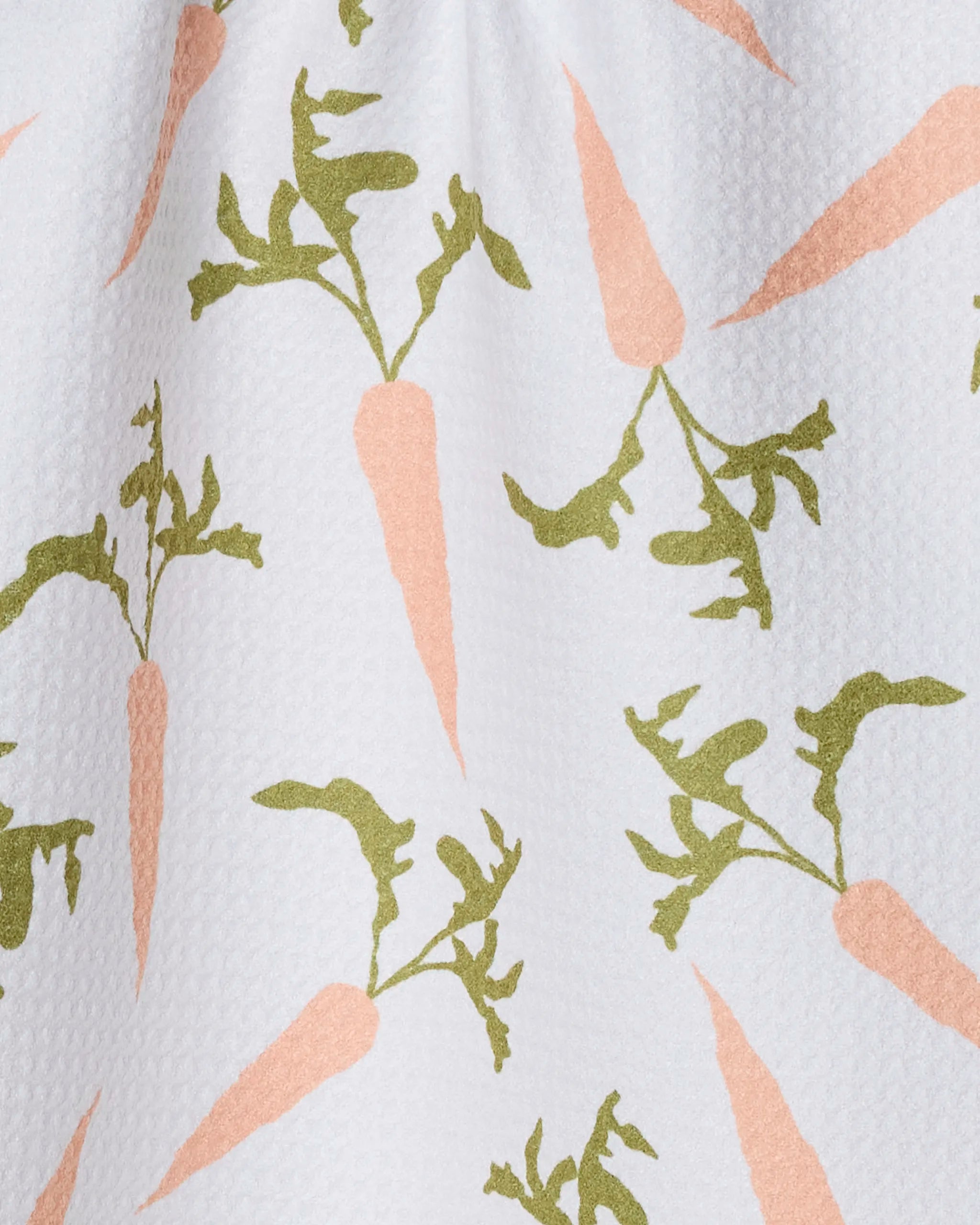 The Geometry Carrot Toss bar towel features a repeated pattern of light orange carrots with green leafy tops on a white textured background and is made from ultra-absorbent recycled materials.