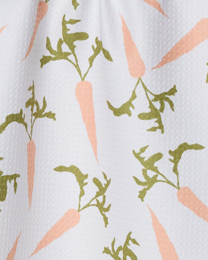 The Geometry Carrot Toss bar towel features a repeated pattern of light orange carrots with green leafy tops on a white textured background and is made from ultra-absorbent recycled materials.