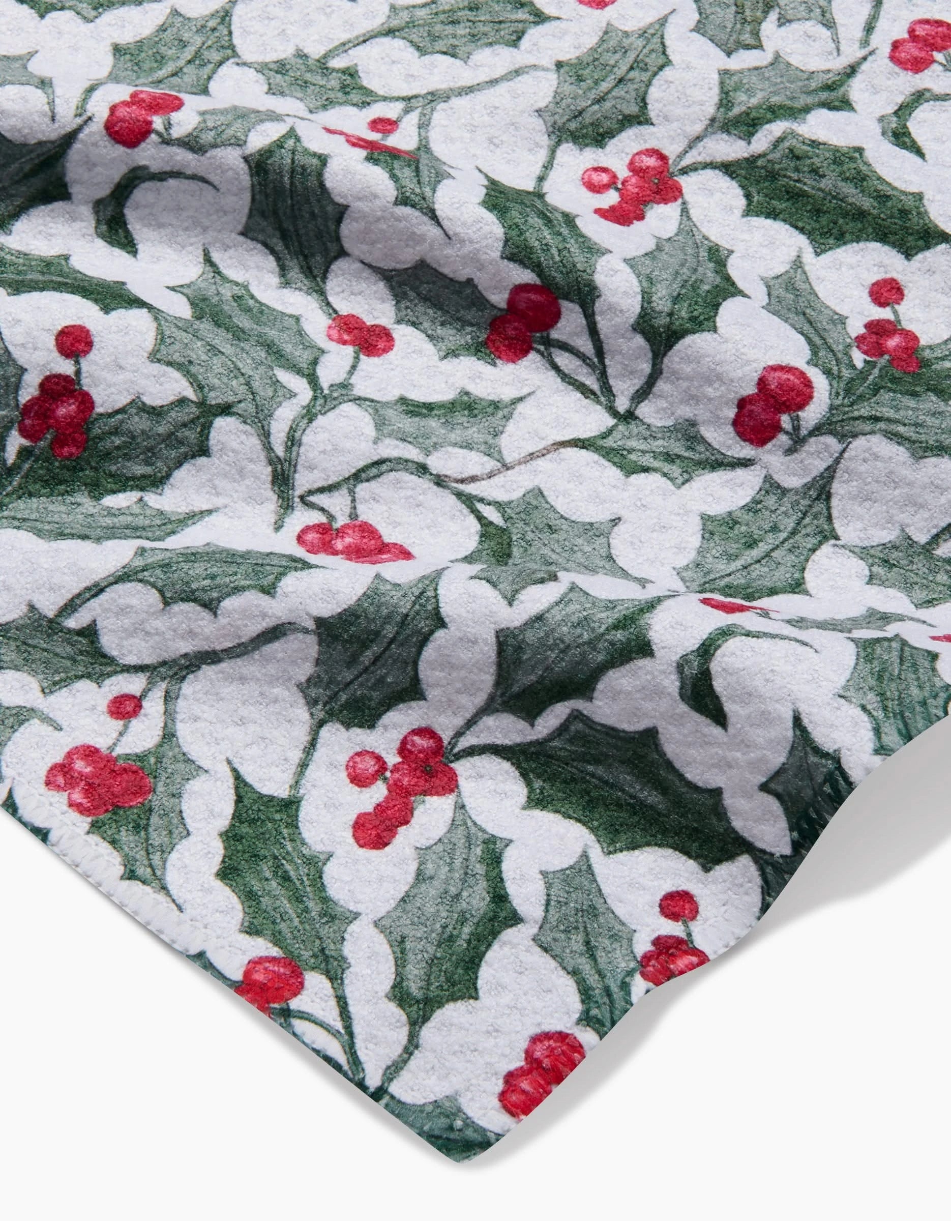 A close-up of the Aubrey Fairchild Christmas Mistletoe towel, ultra-absorbent with a festive white background featuring green holly leaves and red berry clusters.