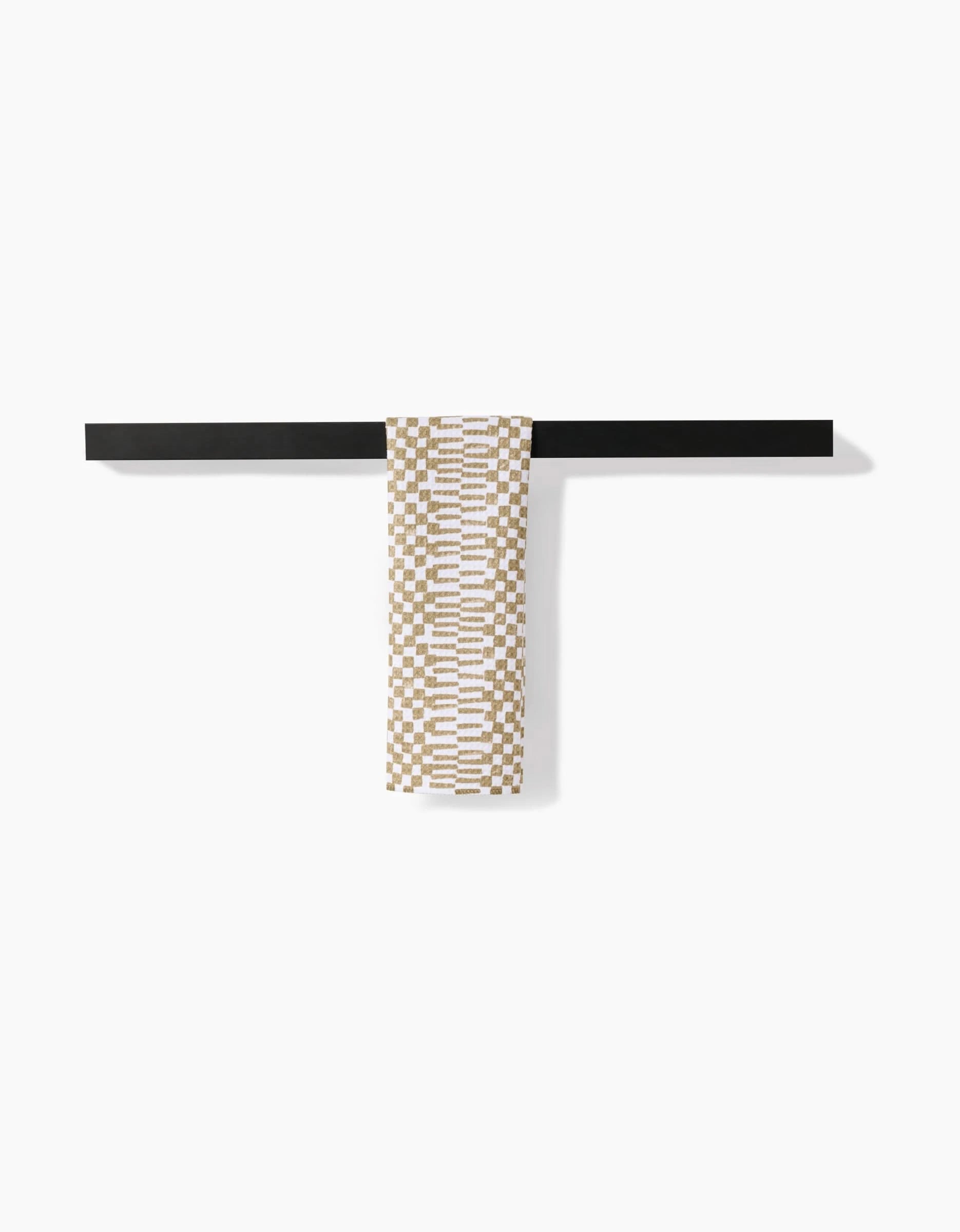 A Chutes Avocado bar towel by Studio Jeannot, featuring a patterned beige and white Geoweave fabric, hangs neatly over a sleek black bar against a plain white background.