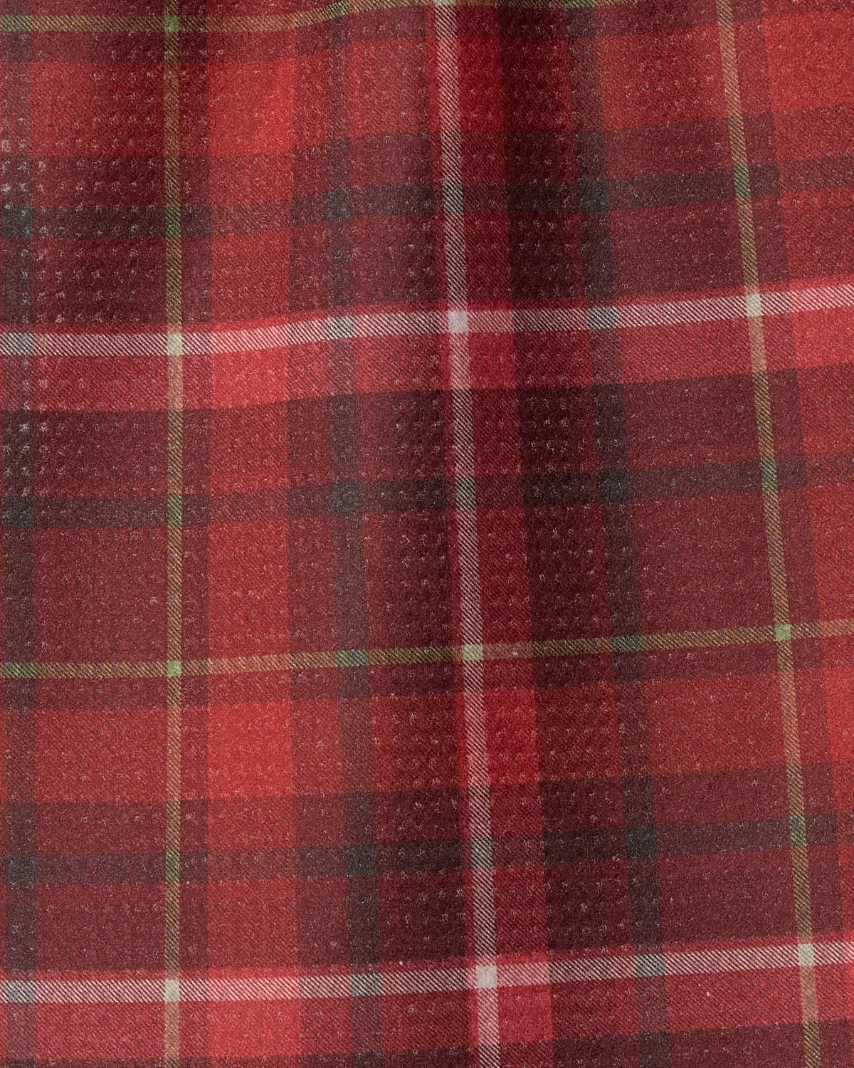 Introducing “Cinnamon Spice” by Geometry: a mini towel crafted from recycled materials, featuring a traditional tartan pattern with horizontal and vertical stripes in shades of red, black, white, and green. The textured fabric is soft and slightly fuzzy to the touch.