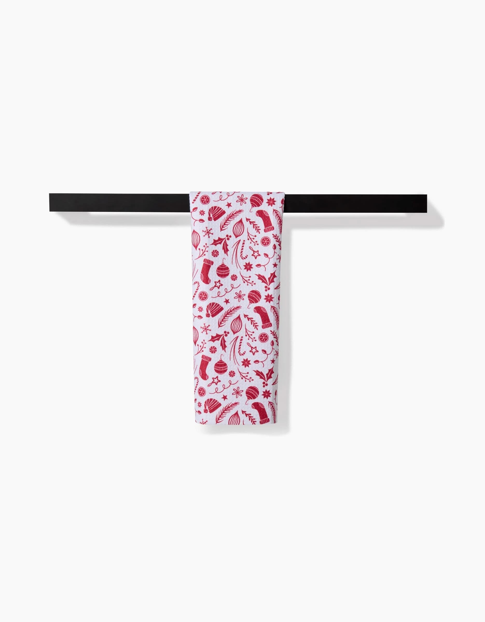 The Sarah Daugherty Classic Christmas Icons Red towel, featuring a red floral and leaf pattern, is neatly draped over a black bar against a plain white background.