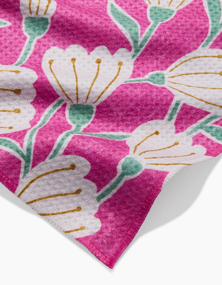 The Clemmie by Amy MacCready is a pink bar towel made from recycled materials, featuring a textured surface and a floral pattern with white flowers, yellow stamens, and green stems.