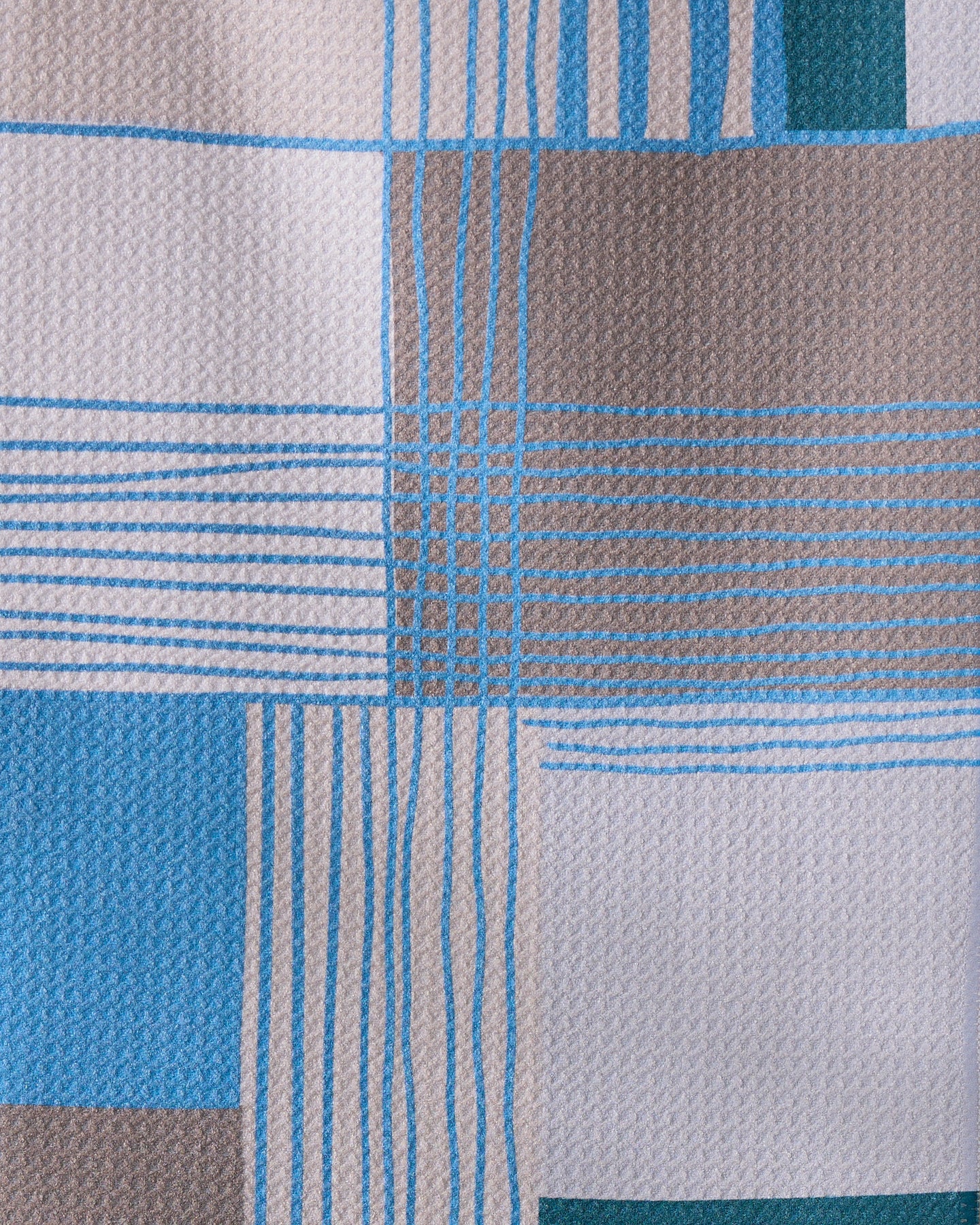 Close-up of the Geometry Cool Blocks towel, featuring an ultra-absorbent texture with intersecting blue, beige, and teal lines and rectangles on a light background.