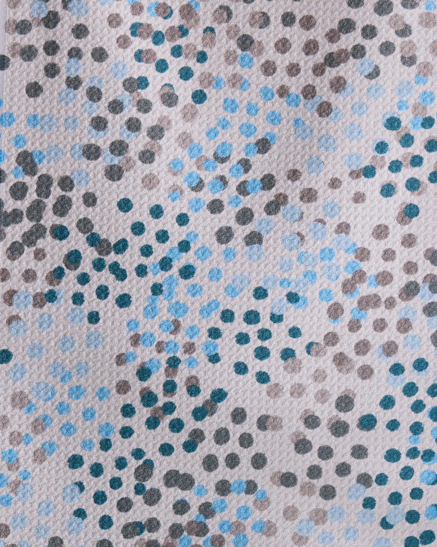 A close-up of Geometry’s Cool Dots recycled kitchen towel, featuring an abstract pattern of irregular blue, black, and gray polka dots on a light background for a modern artistic touch.