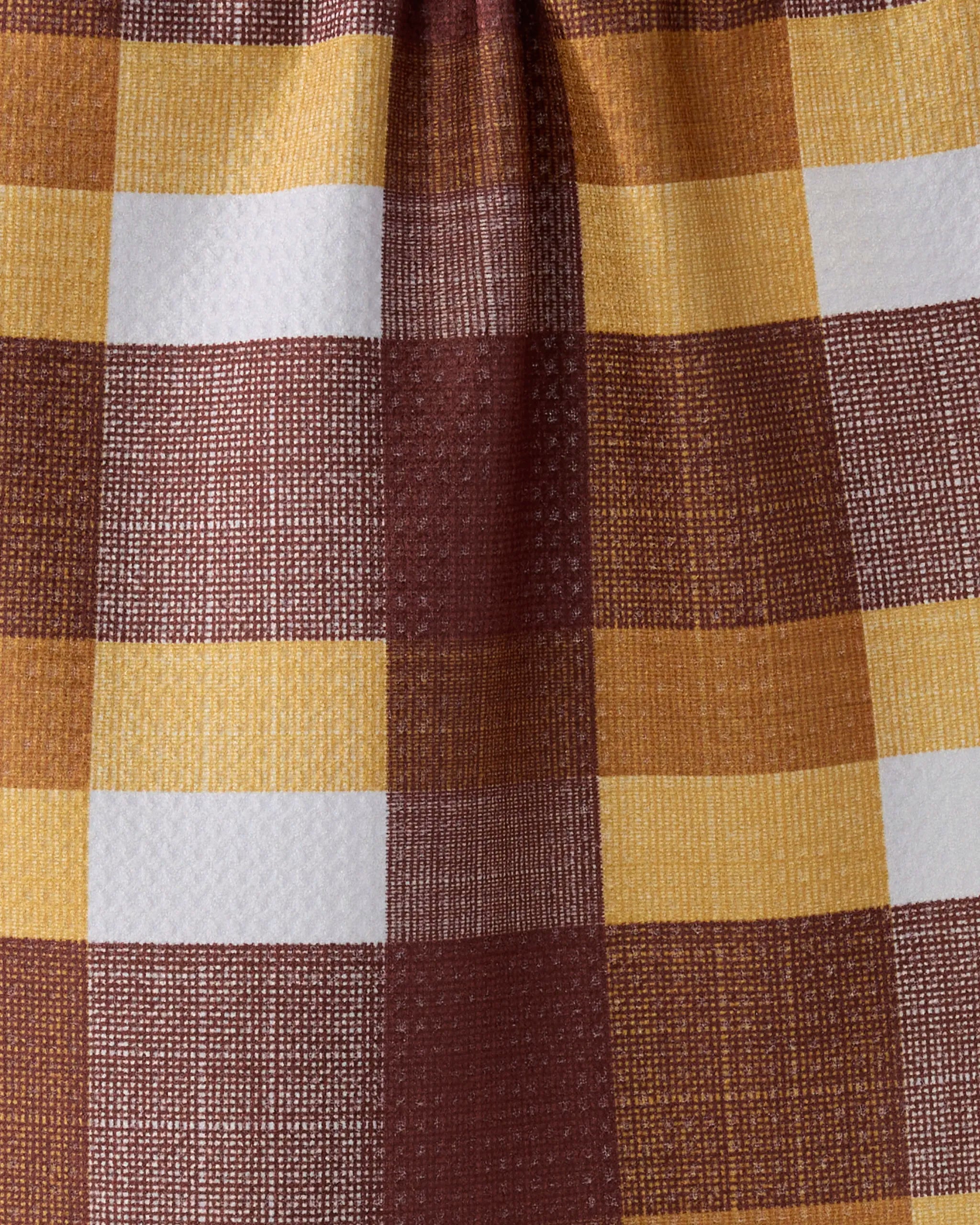 A close-up of Copper Grove by Geometry, a kitchen towel with a brown, yellow, and white checkered pattern. Made from recycled materials, it features a textured surface and a visible vertical crease through the center.