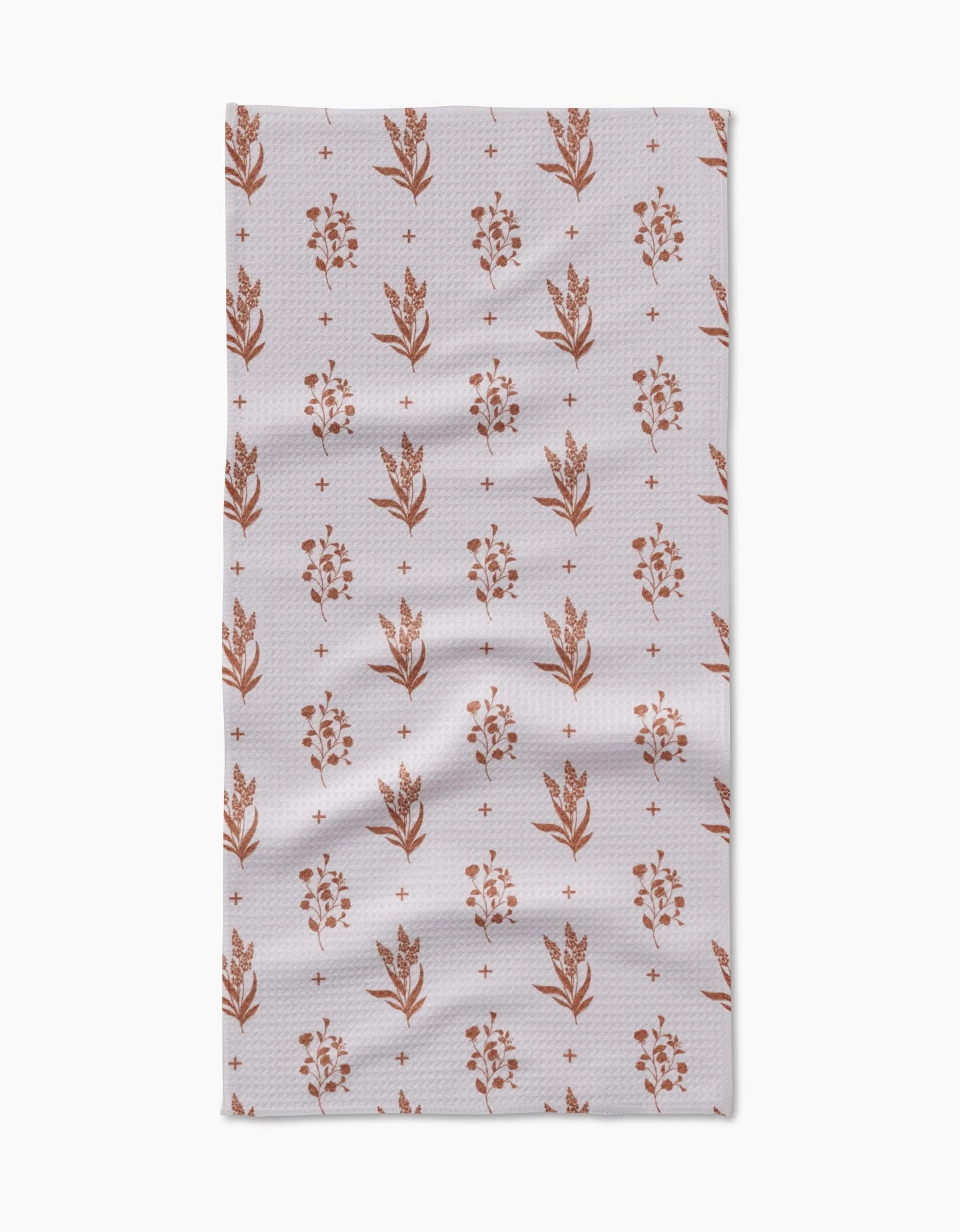 The Country Road by Charlie Rowan Designs is a rectangular Geoweave cloth with small rust floral motifs and plus signs on a light, textured background. Slight wrinkles add to the versatility of this stylish kitchen accessory.