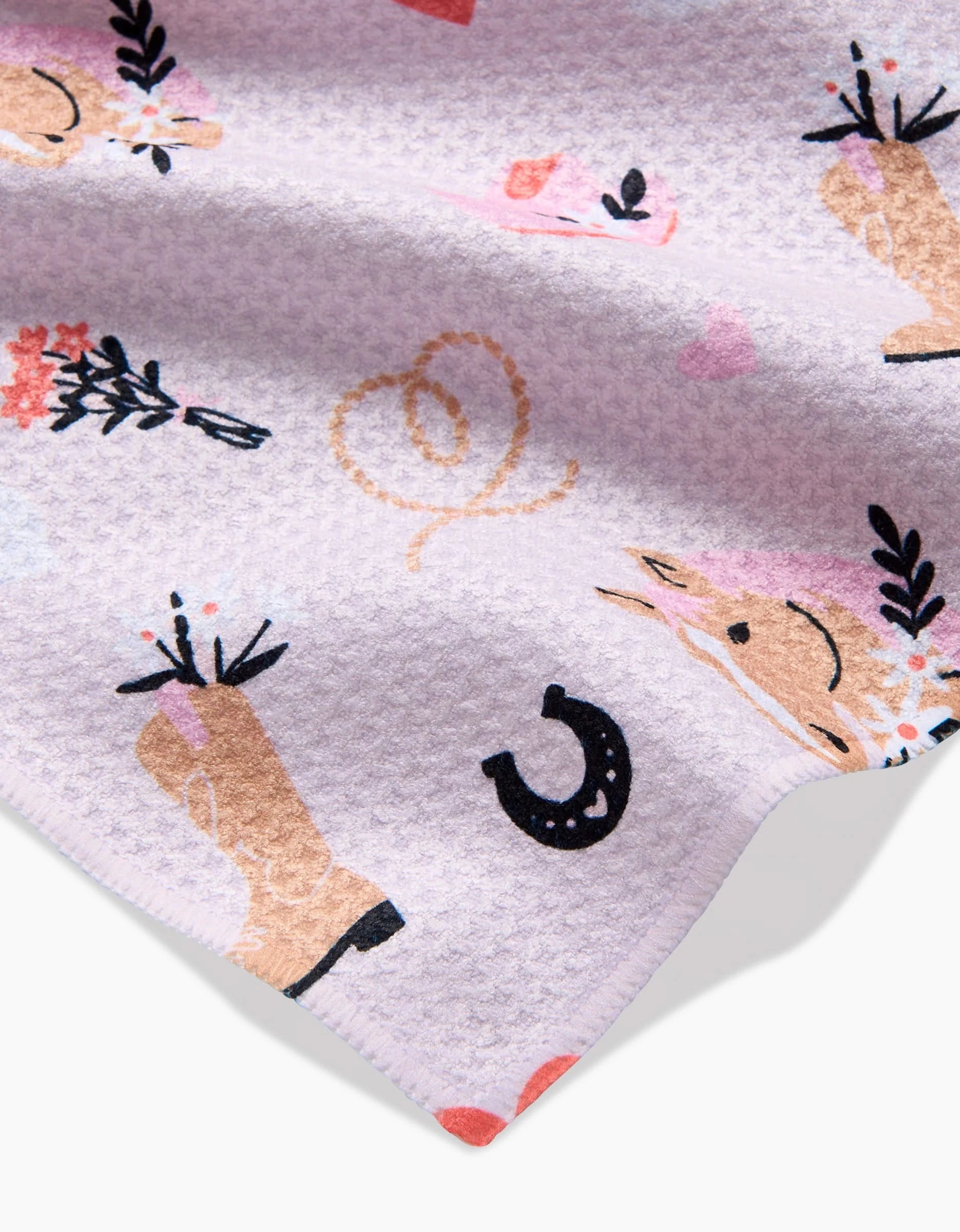 Cowgirl Love by Amberleigh Adoff is a light purple textured fabric made from recycled materials, showcasing playful pastel prints of horses, horseshoes, flowers, and lassos. The fabric’s edge appears in the bottom right corner.