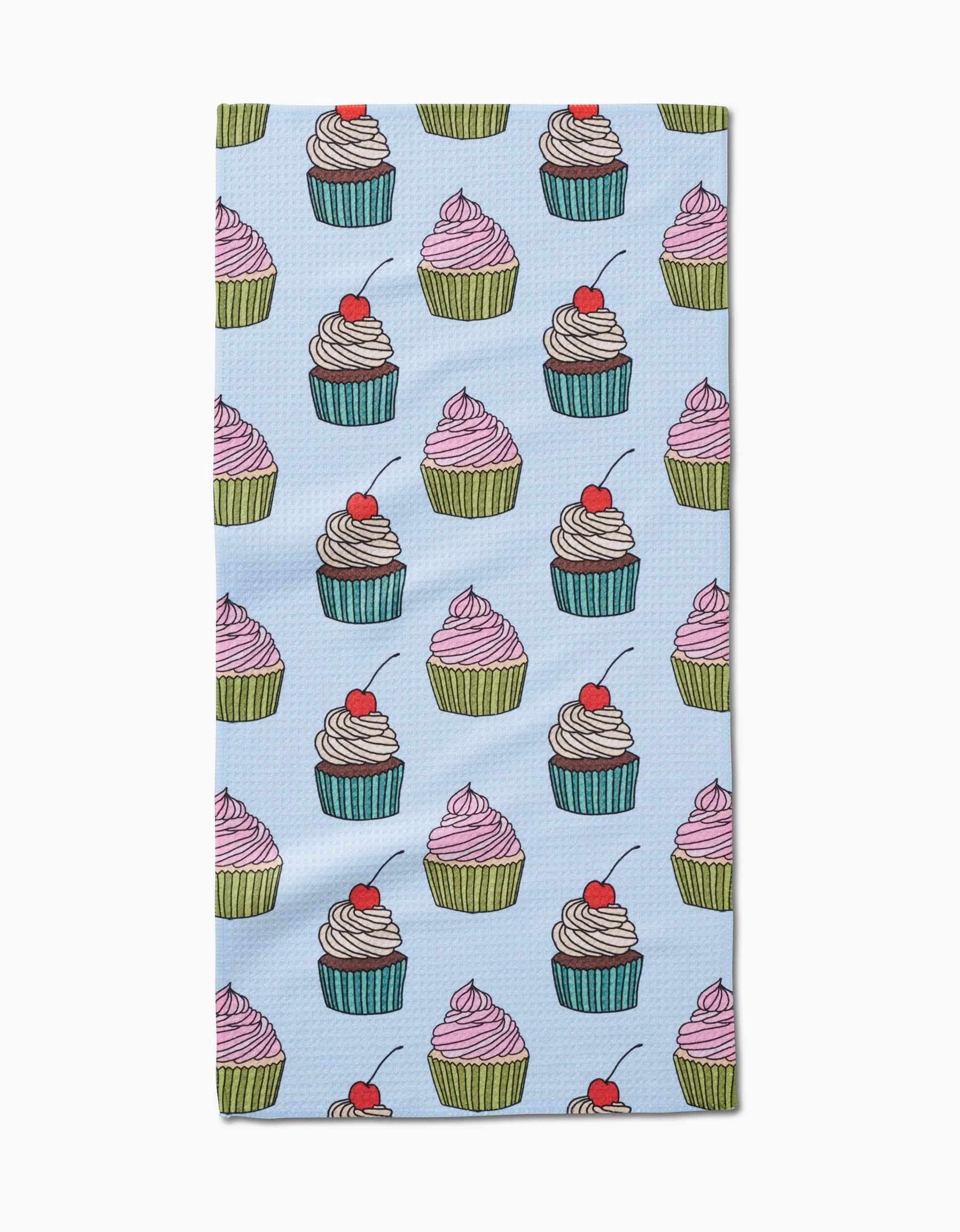 Cupcake Love by Amy Droubay is a light blue bar towel with rows of colorful cupcakes, some topped with cherries, on soft Geoweave fabric.