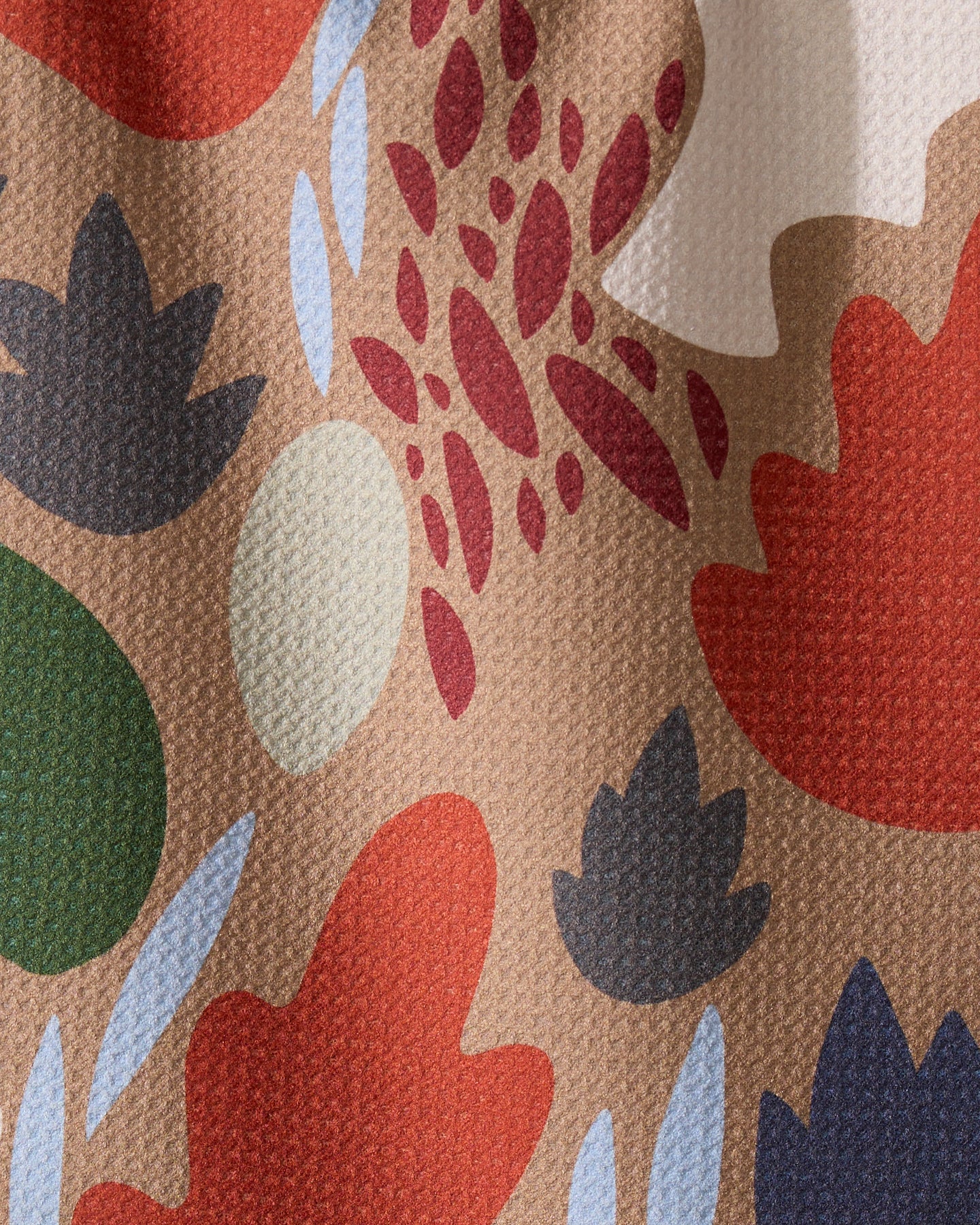 The Cut Paper Leaves Mocha kitchen towel by Geometry features a colorful abstract pattern with red, blue, dark green, beige, and light green leaf-like ovals on a textured recycled background.