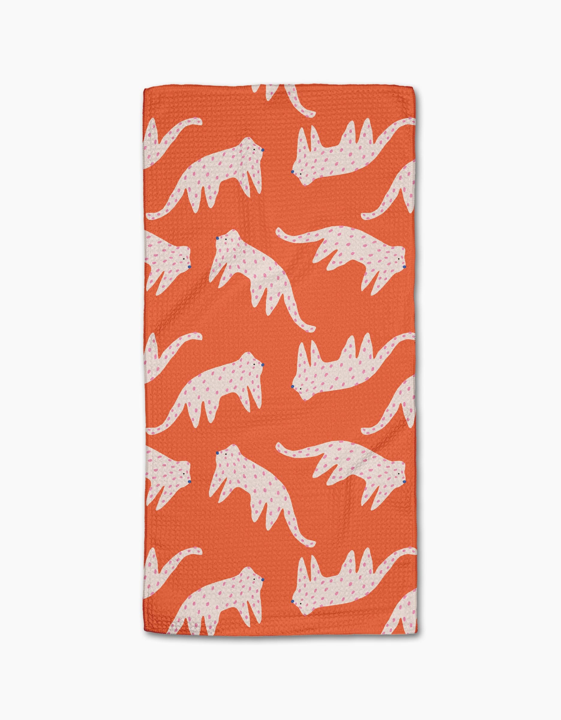 The Cute Cheetah bar towel by Jennifer Bouron is rectangular, orange, and made from recycled materials. It features a repeating pattern of white cheetahs with pink and blue spots in different poses, laid flat on a white background.