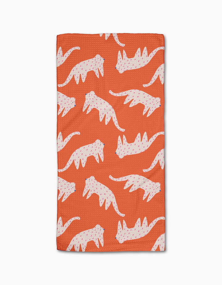 The Cute Cheetah bar towel by Jennifer Bouron is rectangular, orange, and made from recycled materials. It features a repeating pattern of white cheetahs with pink and blue spots in different poses, laid flat on a white background.