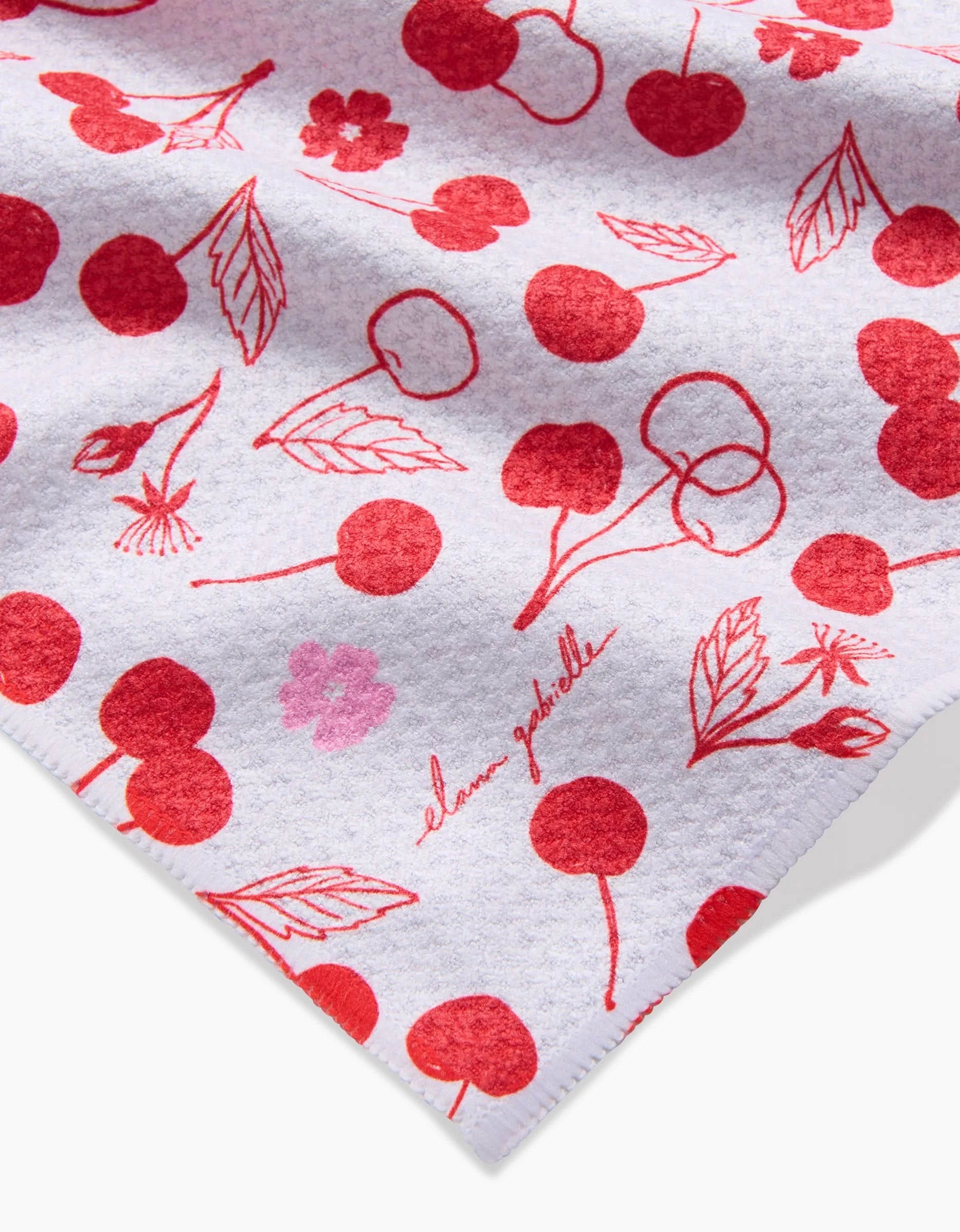 The Cute Cherry bar towel by Elana Gabrielle is made from ultra-absorbent recycled materials, featuring a white textured design with red cherries, cherry blossoms, and leaves. The brand name is written in red cursive in the bottom right corner.