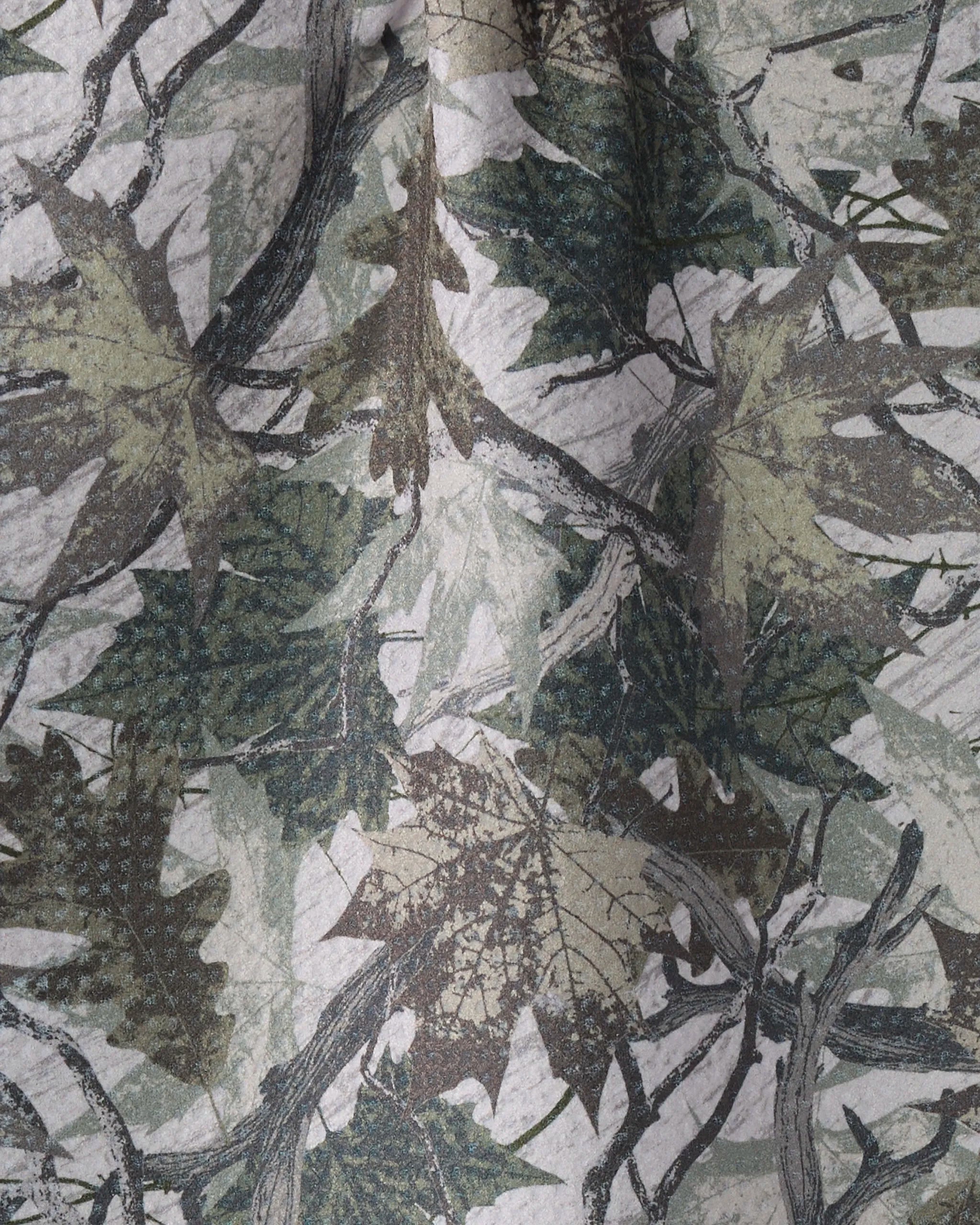 A close-up of Geometry's Dad Camo bar towel, made from recycled materials and featuring a camouflage design with overlapping green, brown, and gray leaves and branches.