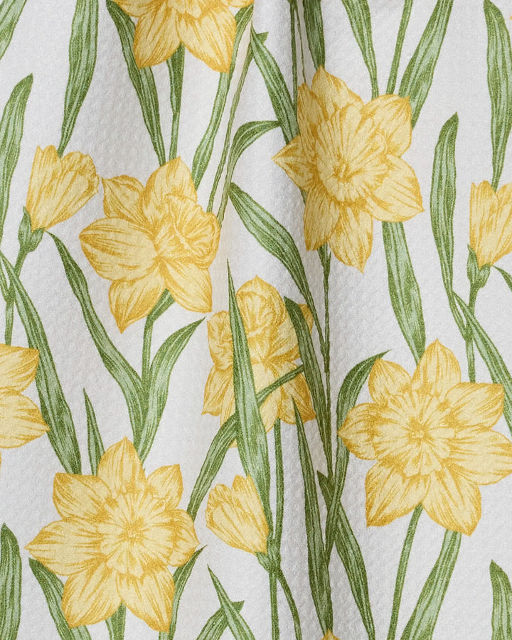 Geometry’s “Daffodil Darling” bar towel showcases yellow daffodils and green leaves on a white textured background, made from recycled materials.