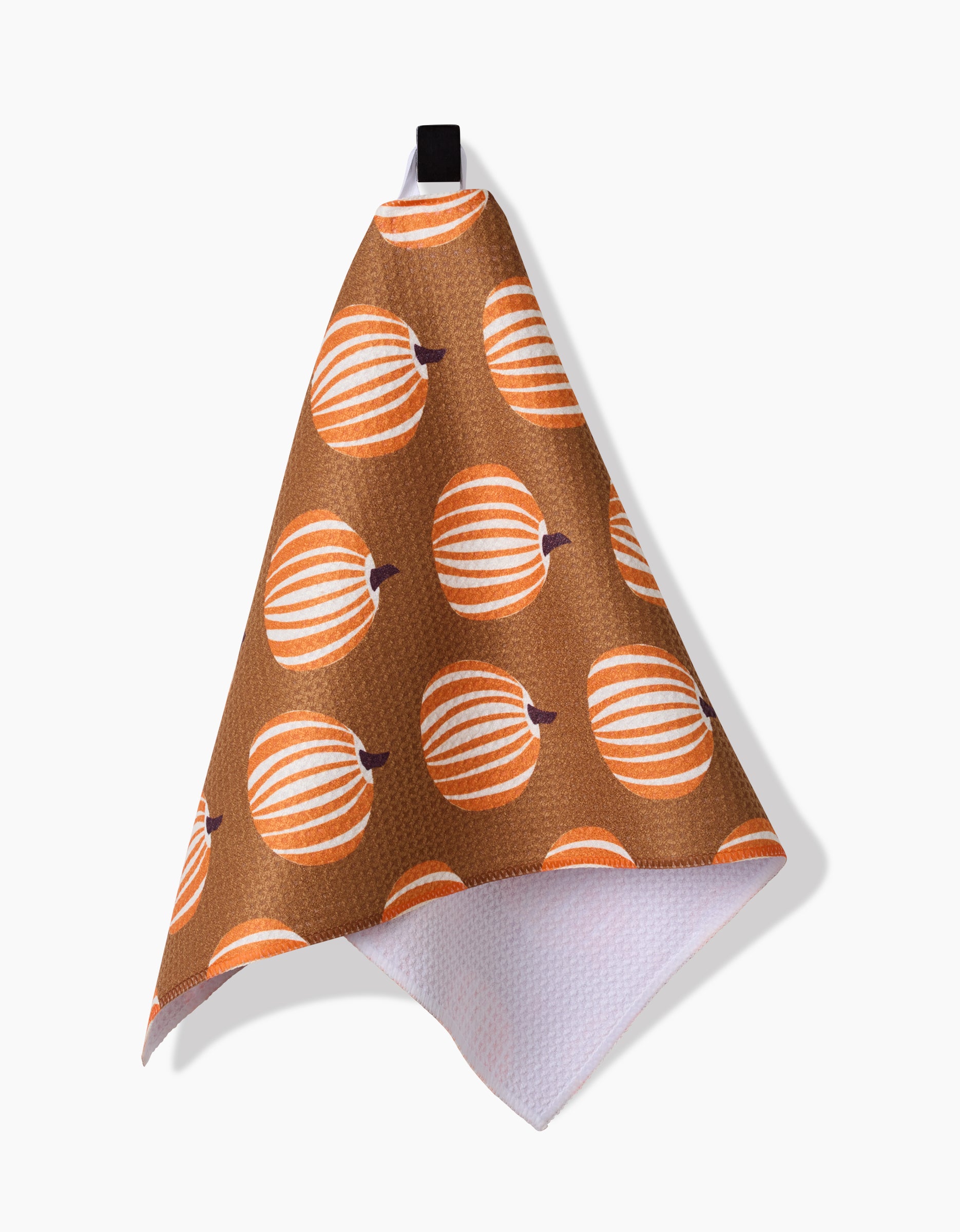 The Dancing Pumpkins bar towel by Lizzie Clark features an orange and white pumpkin pattern on brown Geoweave fabric, hangs from a black loop, and has a white reverse side.