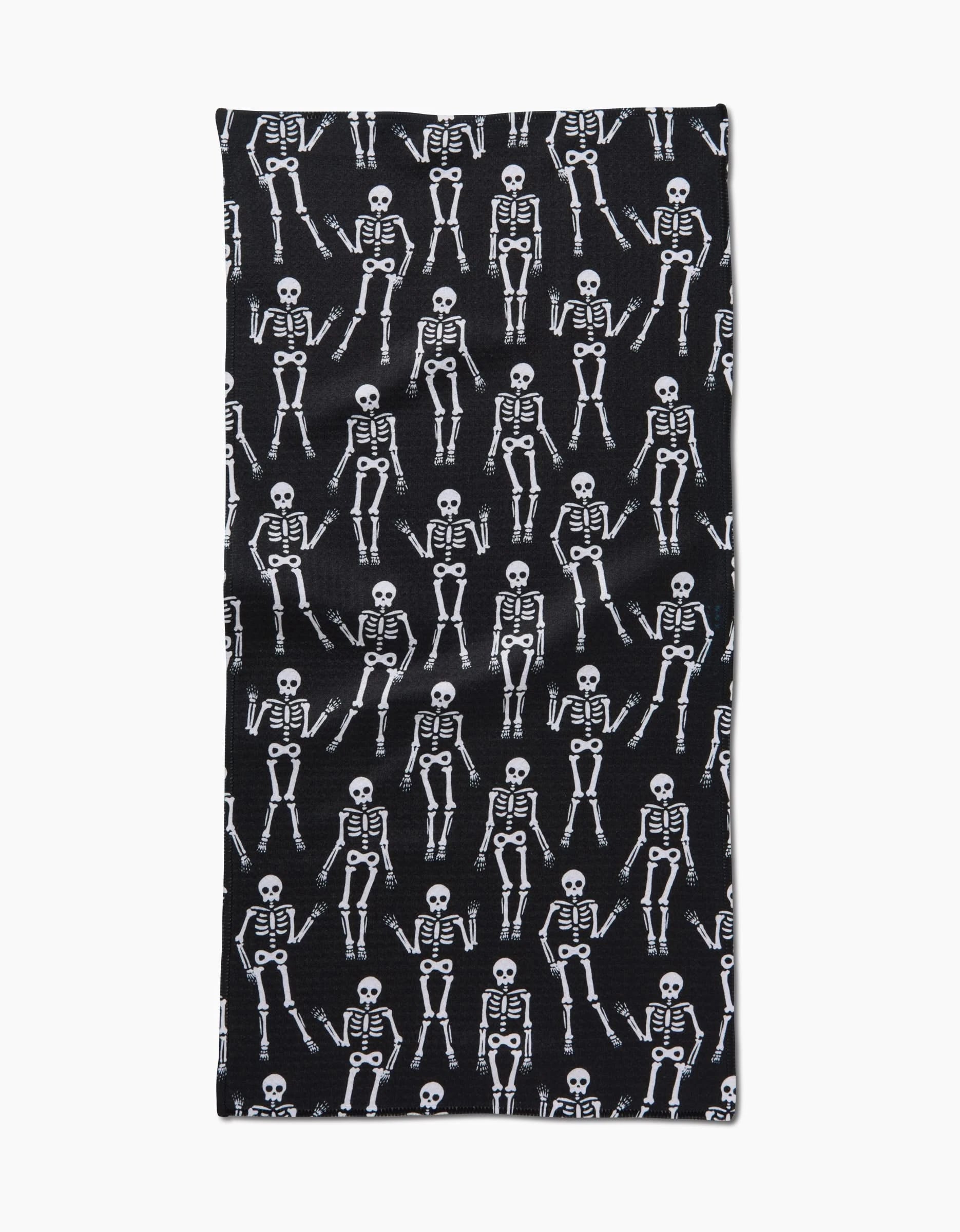 The Dancing Skeletons Black White bar towel by Hufton Studio is a rectangular, ultra-absorbent black towel made from recycled materials, featuring playful white cartoon skeletons in a repeating pattern.
