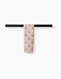 The Dancing Vines bar towel by Charlie Rowan Designs, featuring a brown floral and leaf pattern, is neatly draped over a simple black towel bar against a plain white background.