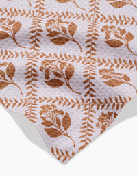The Dancing Vines towel by Charlie Rowan Designs features a soft, ultra-absorbent fabric with brown botanical leaves and flowers in a grid on a white background, showcased with its finished edge in the corner.