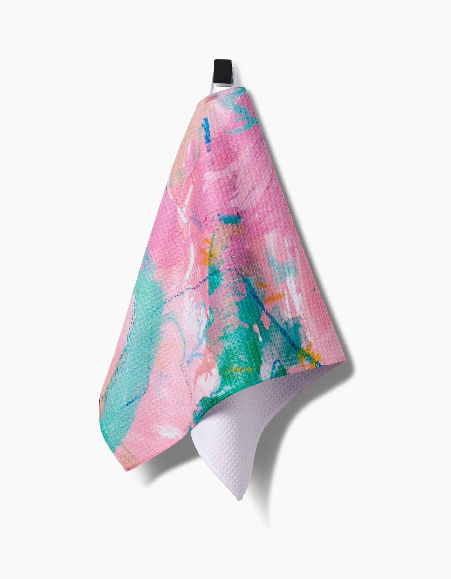 The Sarah Holden Daughter Bar Towel features a vibrant abstract pink, green, and blue pattern. Hanging from a black loop with its textured Geoweave fabric and inner white side visible, it stands out against a white background.