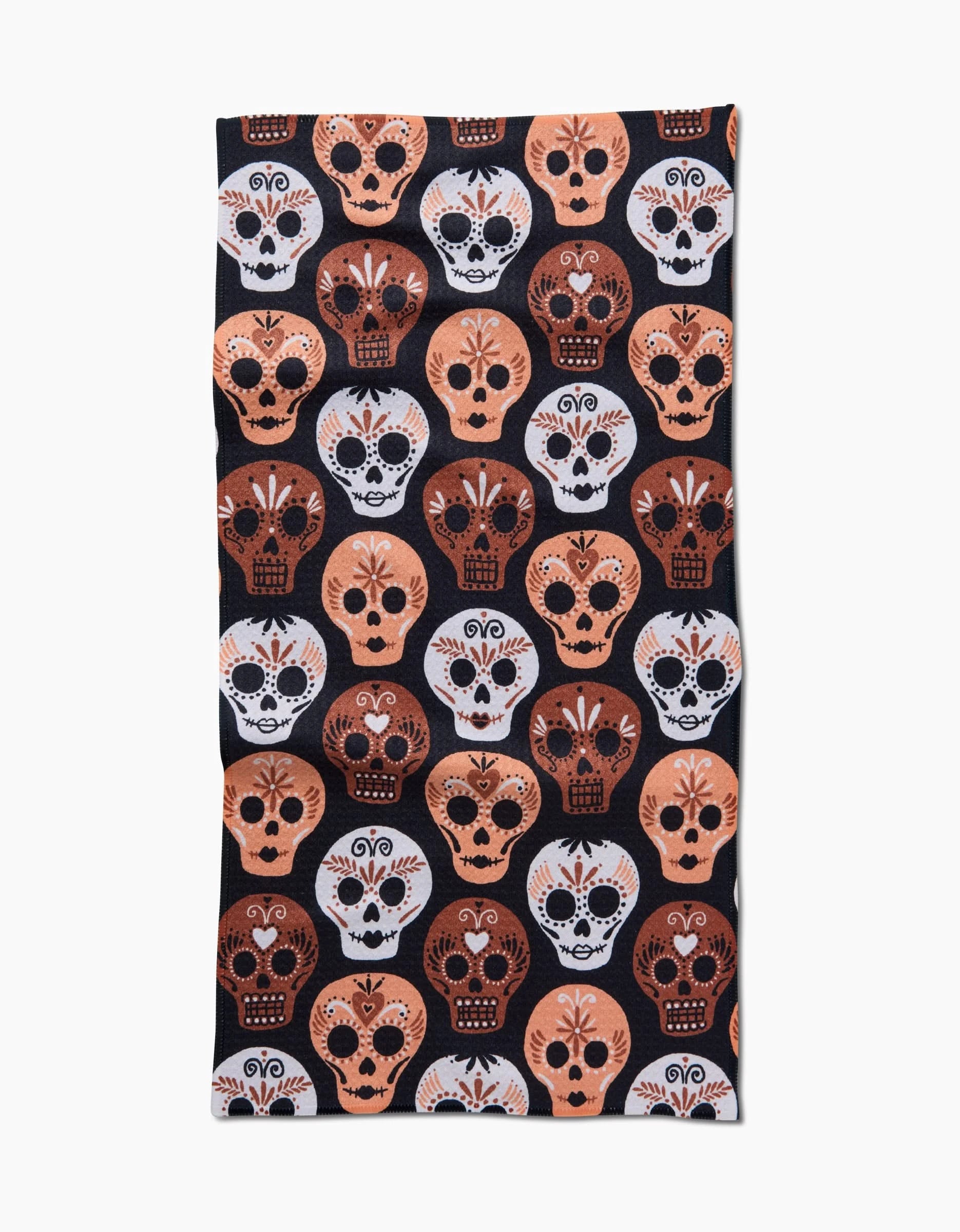 The Day Of The Dead Skulls towel by Hufton Studio is a rectangular, ultra-absorbent bar towel featuring a repeating pattern of stylized sugar skulls in white, orange, and brown on black, inspired by Día de los Muertos.