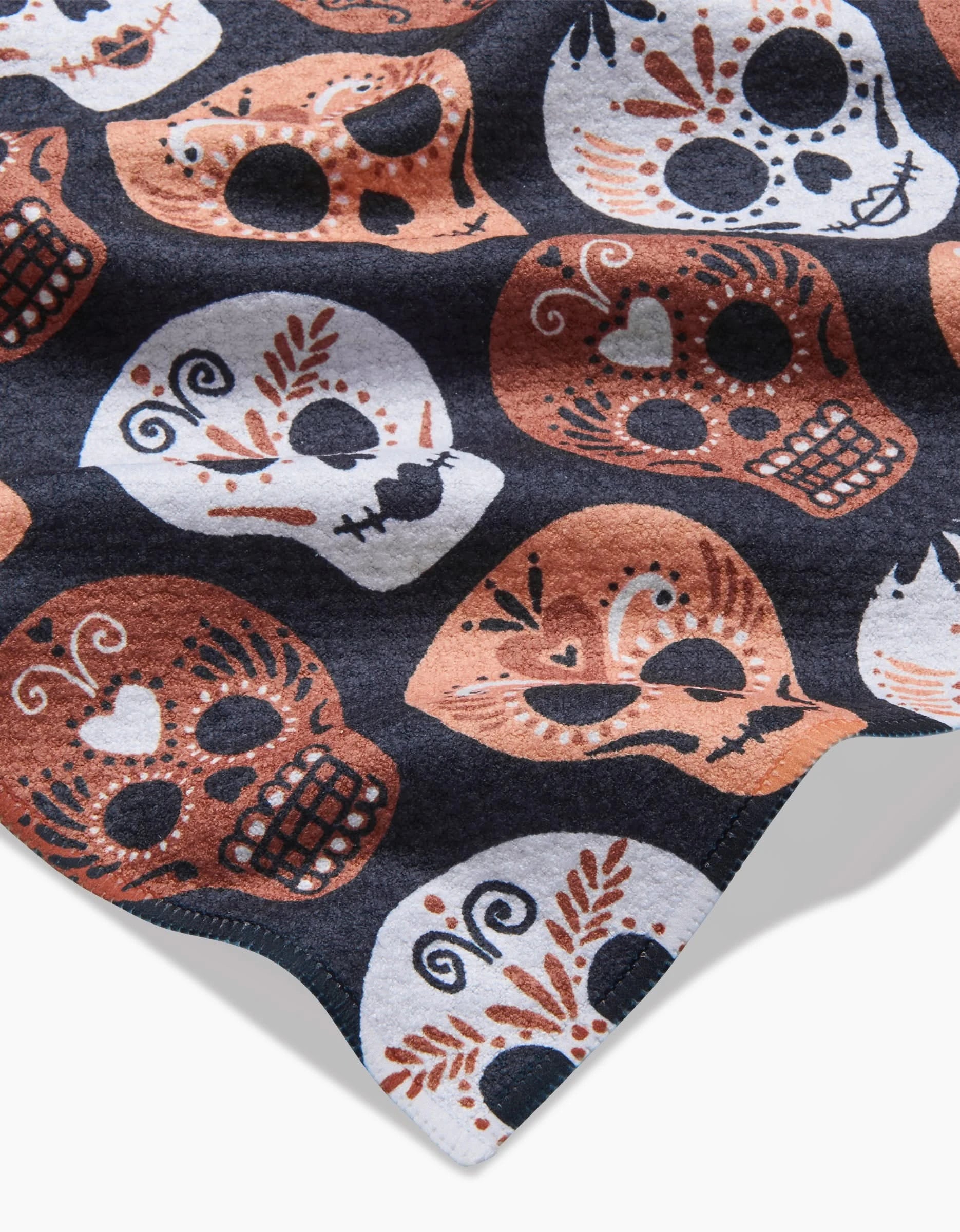 The Day Of The Dead Skulls recycled kitchen towel by Hufton Studio features white and orange stylized skulls with floral and heart details on a dark background.