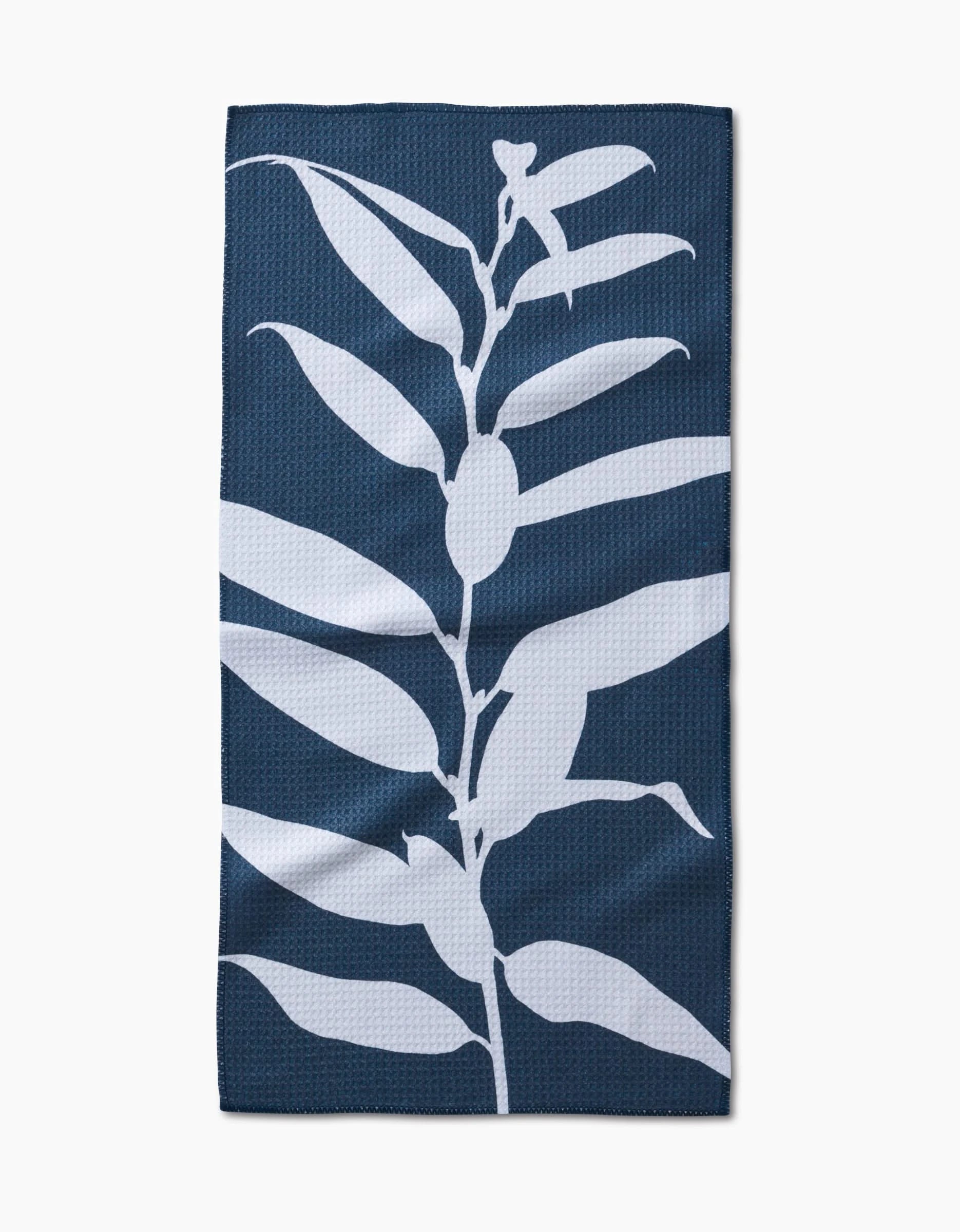 The Doghobble by PrintedPlant is a dark blue bar towel made from recycled materials, featuring a vertical white silhouette of a leafy plant design at its center.