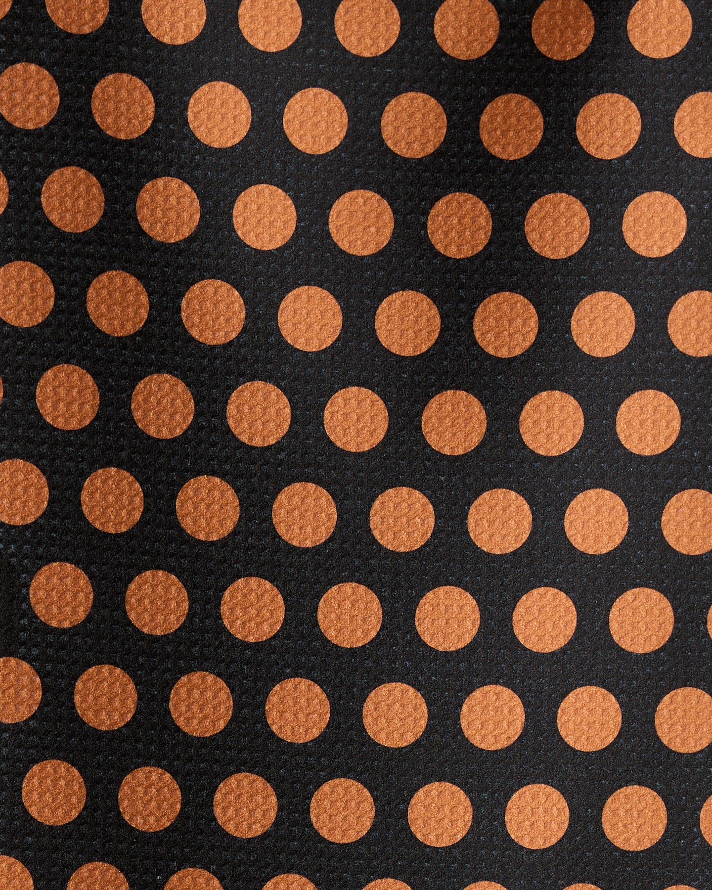 Close-up of Geometry’s Dot Noir bar towel, crafted from recycled materials. It features evenly spaced orange polka dots on a black background and a textured, ultra-absorbent fabric.