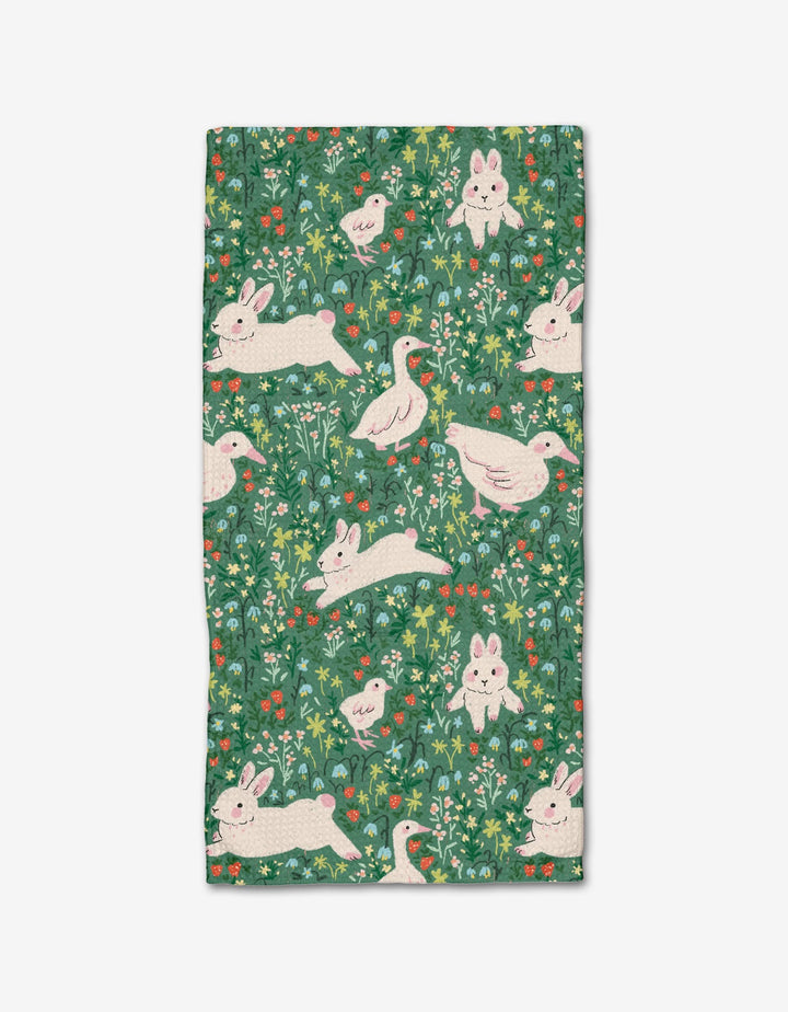 The Easter Meadow bar towel by Janna Sue Design features Geoweave™ fabric with playful white rabbits and ducks, green grass, leafy details, and colorful flowers on a green background with intricate plant motifs.
