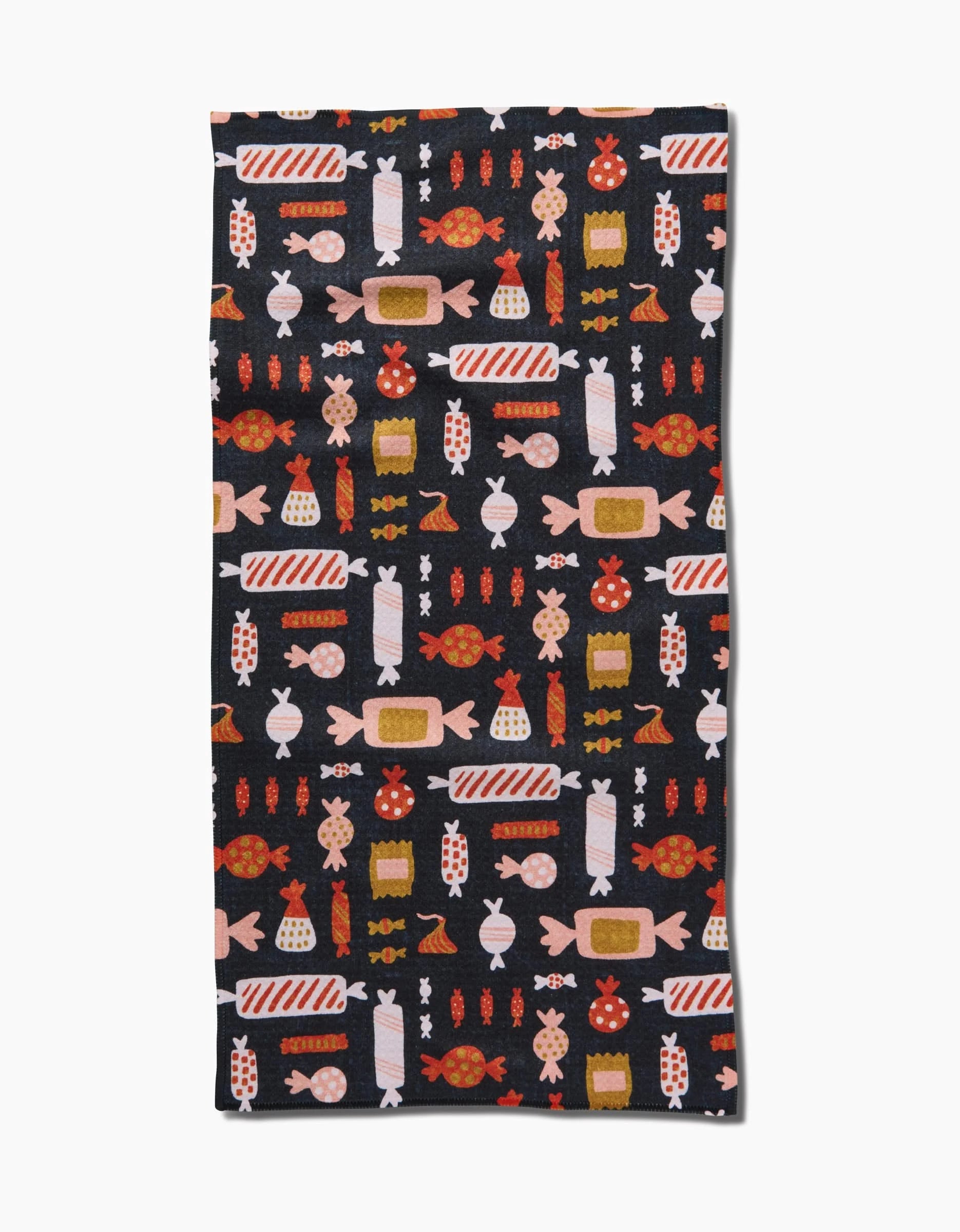 The Edwina towel by Amy MacCready is a rectangular black ultra-absorbent towel with a colorful repeating pattern of wrapped candies in red, orange, yellow, pink, and white. Shown flat on a white background.