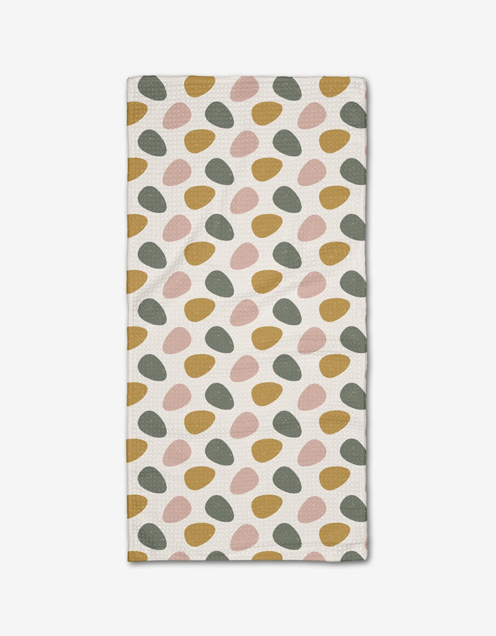 The Egg Hunt bar towel by Charlie Rowan Designs features irregular oval patterns in mustard yellow, blush pink, and sage green on soft Geoweave fabric, arranged in diagonal rows across a white background.
