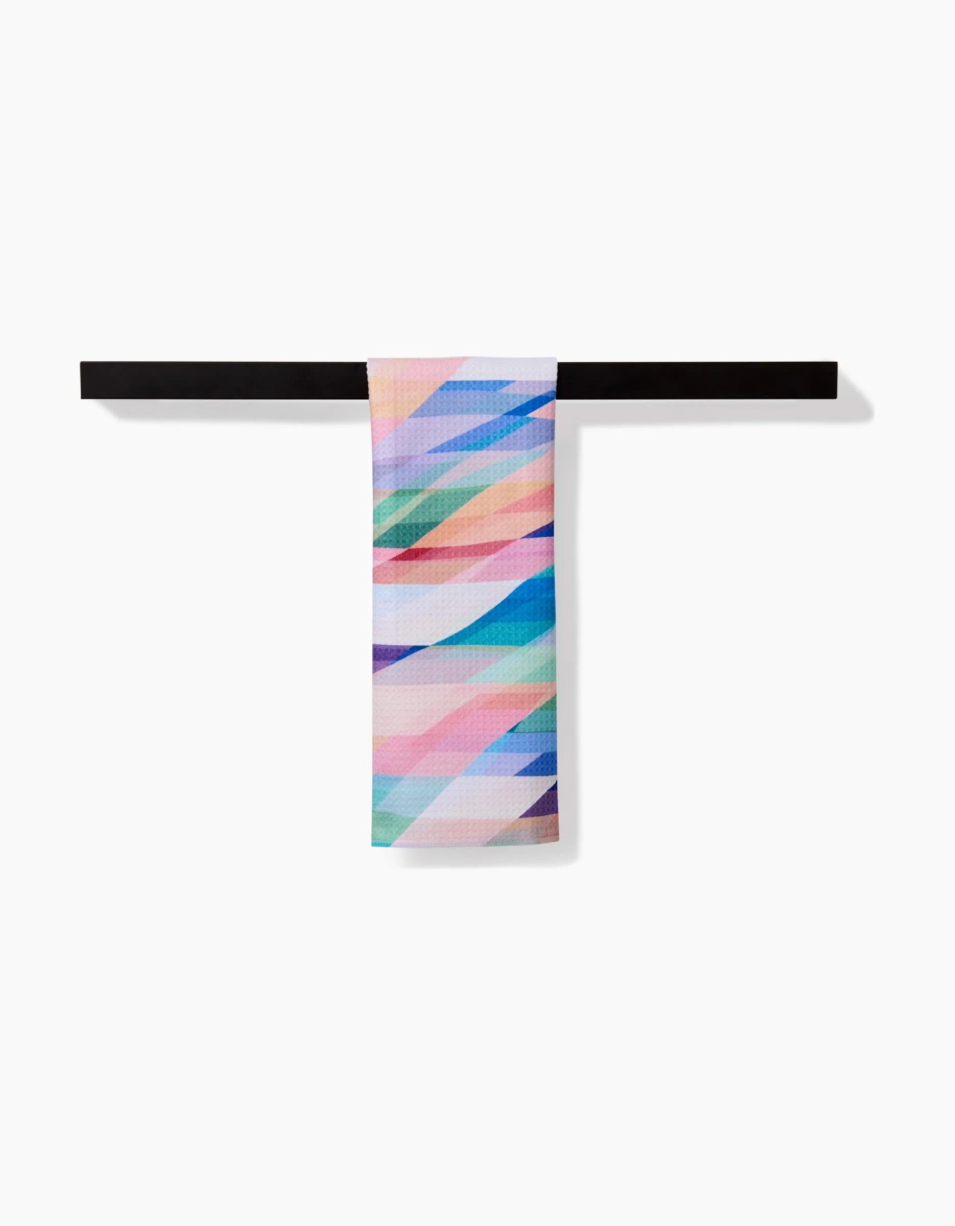 The Rachel Parker Eventide Bar Towel features diagonal pastel stripes in a geometric pattern on soft Geoweave fabric, shown draped over a black horizontal bar against a white background.