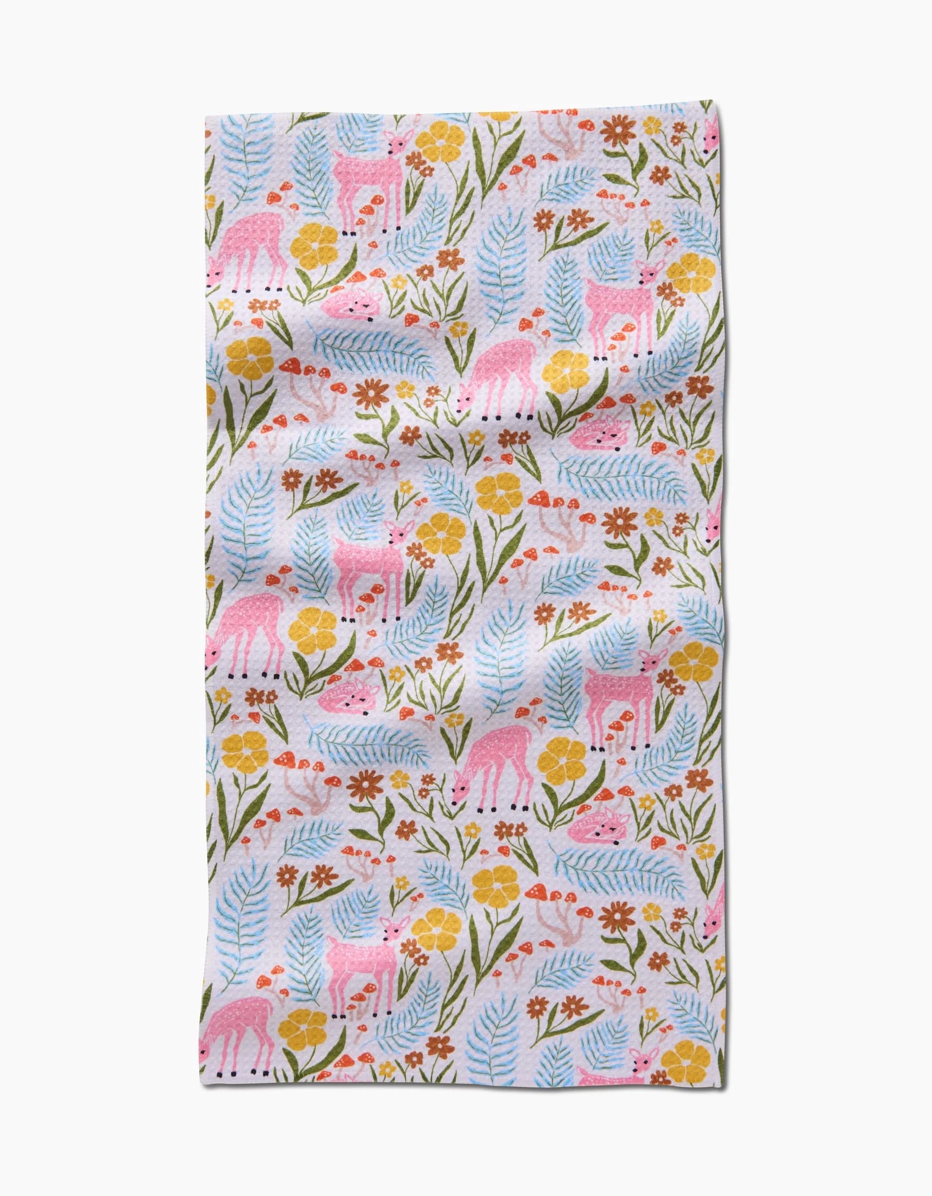 The Fern and Fawn Bar Towel by Kayla Ann features pink deer, colorful flowers, blue leaves, and green stems on white Geoweave fabric with soft folds and a playful pattern.