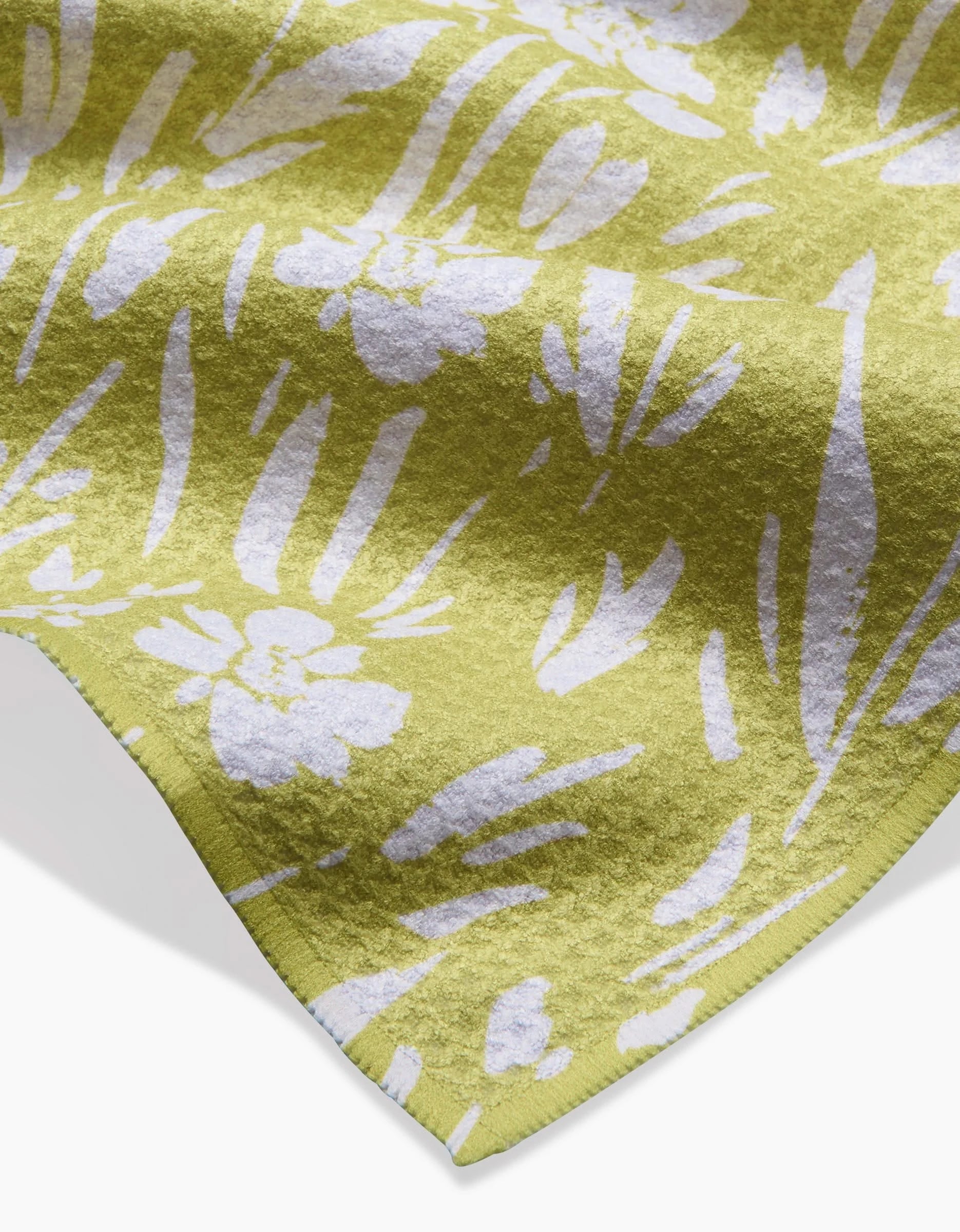 A close-up of the Ashley Celena Field of Wildflowers Bar Towel, featuring yellow Geoweave fabric with a white floral and leaf pattern, textured material, and a slightly curved edge.