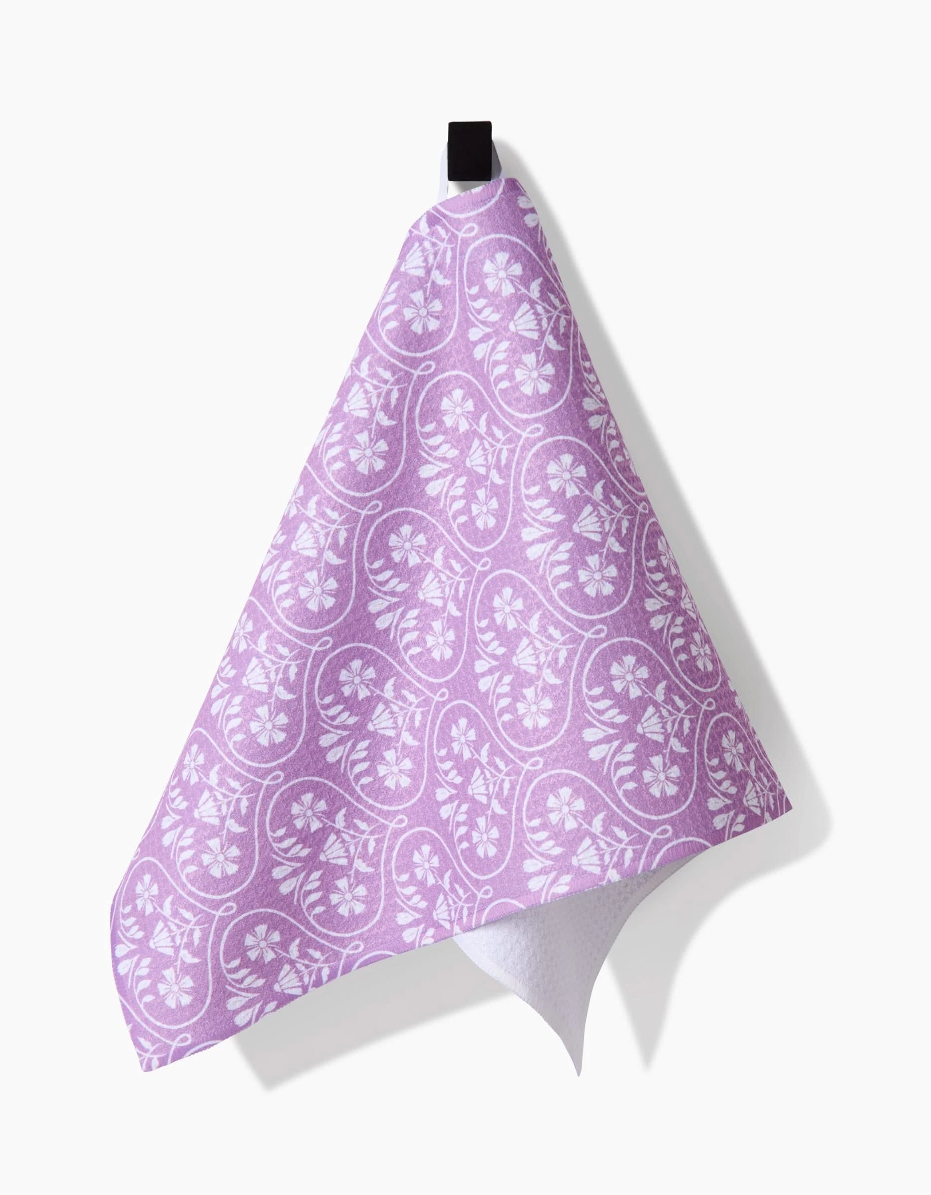 The Hufton Studio Floral Vine Hearts Bar Towel, crafted from Geoweave fabric in purple with a white paisley and floral pattern, hangs from a black loop against a white background.