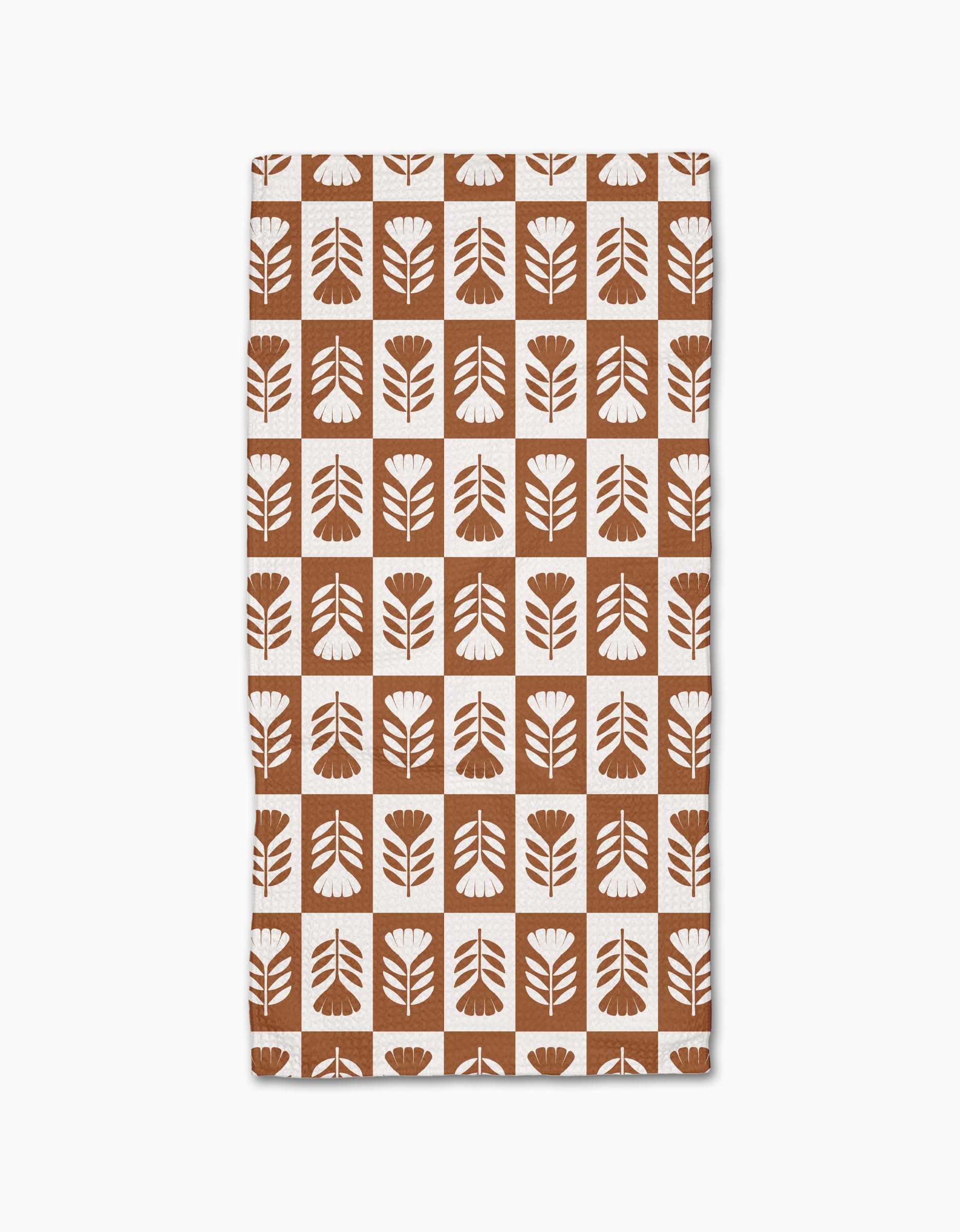 Introducing the Flower Patch bar towel by Charlie Rowan Designs—a brown and white rectangular towel made from recycled materials, featuring stylized floral shapes in a checkerboard pattern.