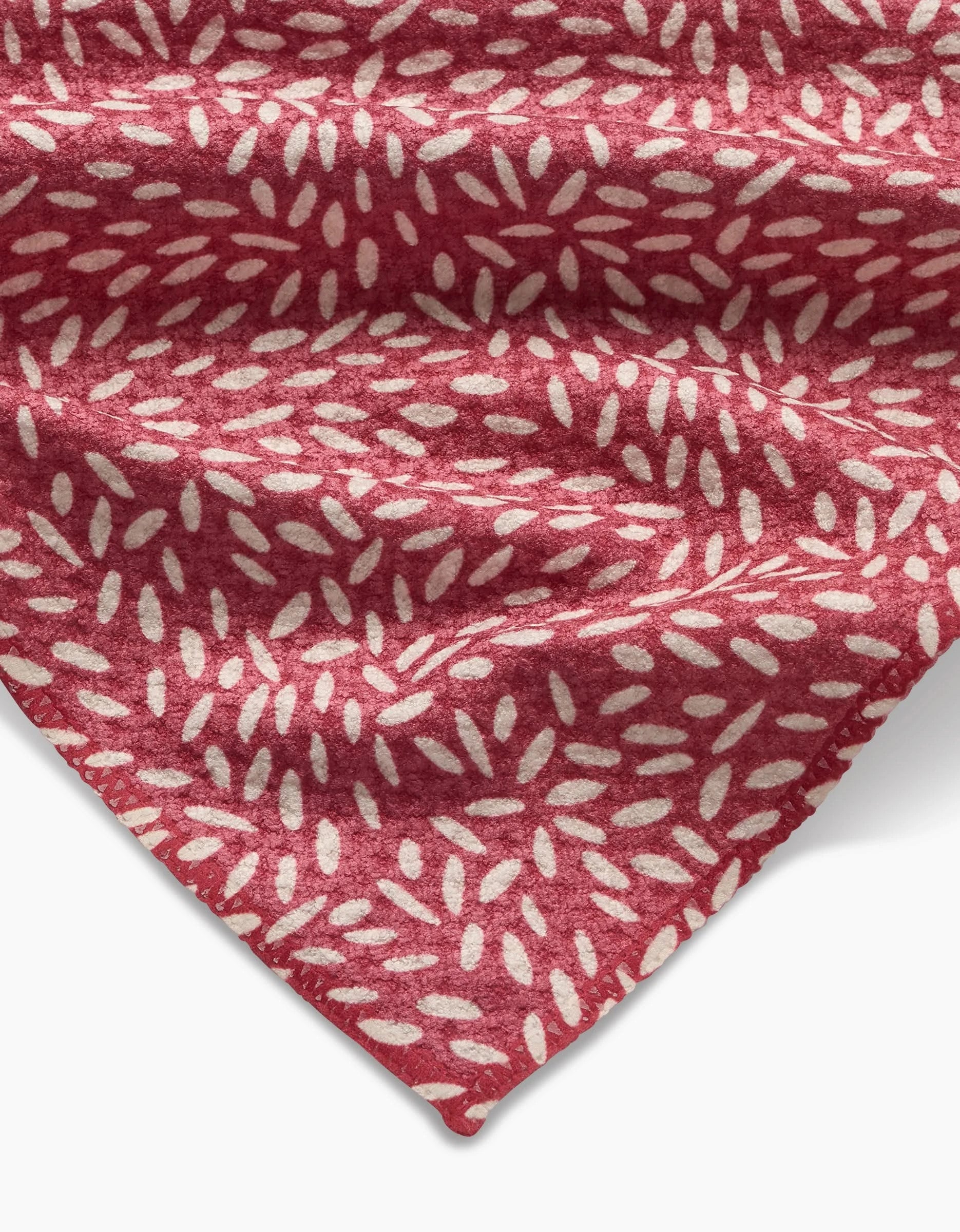 A close-up of Amita Nair’s Flower Seeds packaging in red, featuring small white oval shapes. The stylish branding is visible in the lower corner, and the package fabric shows slight wrinkles for added texture.