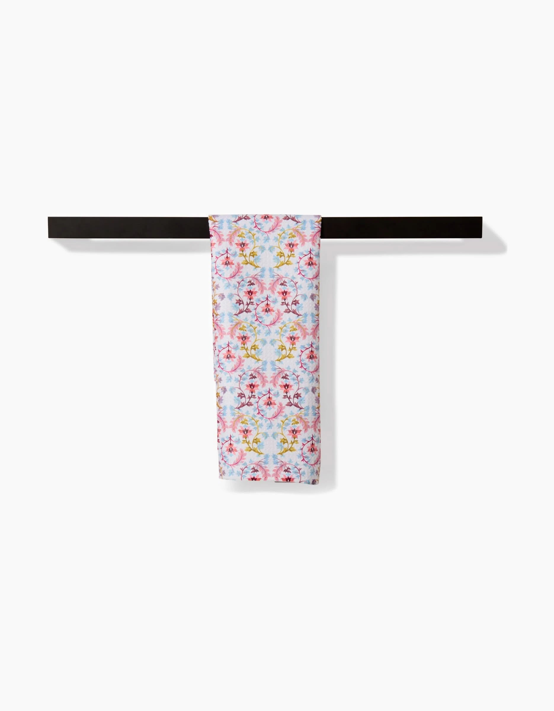 The Folk Tapestry bar towel by Maayan Alper-Swan, featuring a pastel floral pattern and made from recycled materials, hangs neatly over a black rod against a plain white background.