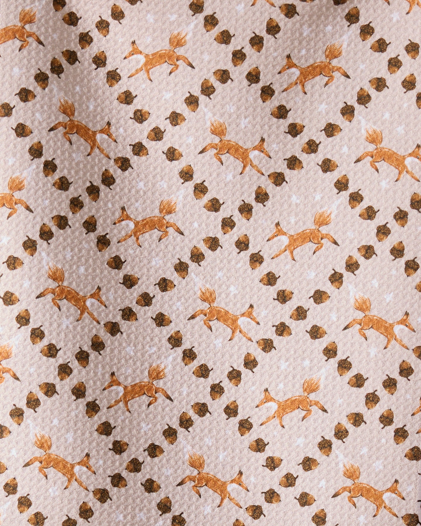 The Geometry Foxes and Twinkles bar towel showcases orange running foxes and brown twinkles in a diagonal grid on light beige, crafted from recycled materials.