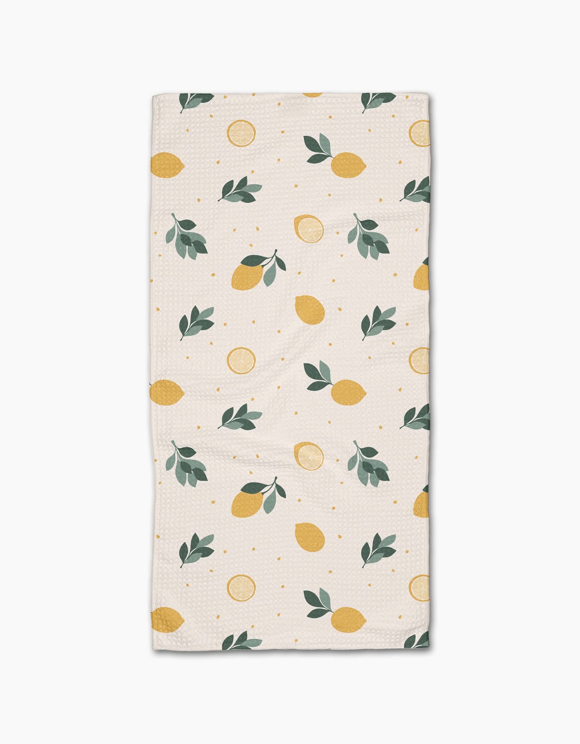 The Freshly Picked Bar Towel by Sara Mari is a rectangular beige towel with yellow lemons, lemon slices, green leaves, and dots. Made from Geoweave fabric for superior absorbency and durability.