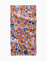The Fruits Party bar towel by Claire Iglesias showcases a vibrant abstract fruit design with cherries, berries, and citrus in bold hues on brown Geoweave fabric for lasting durability.