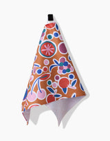 The Claire Iglesias Fruits Party Bar Towel features a vibrant fruit and floral pattern in red, pink, blue, and purple on brown Geoweave fabric, displayed hanging from a black loop against a white background.