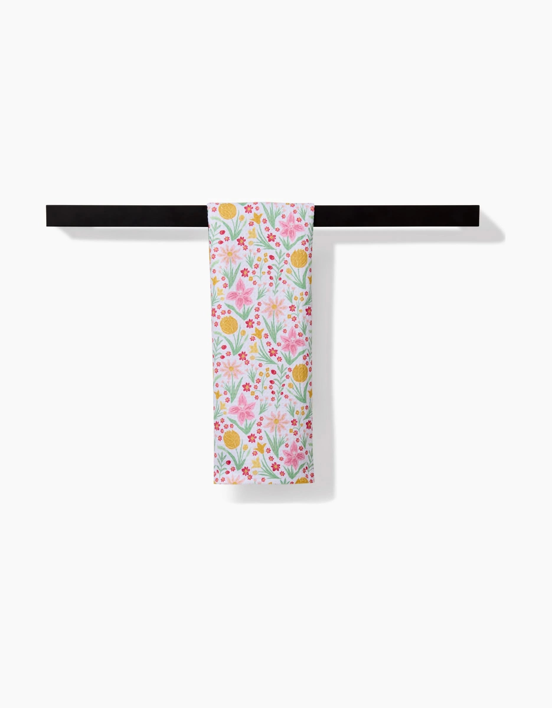 The Danelys Sidron Garden of Light bar towel, crafted from recycled materials with pink, yellow, and green floral patterns, hangs on a black towel bar against a plain white background.