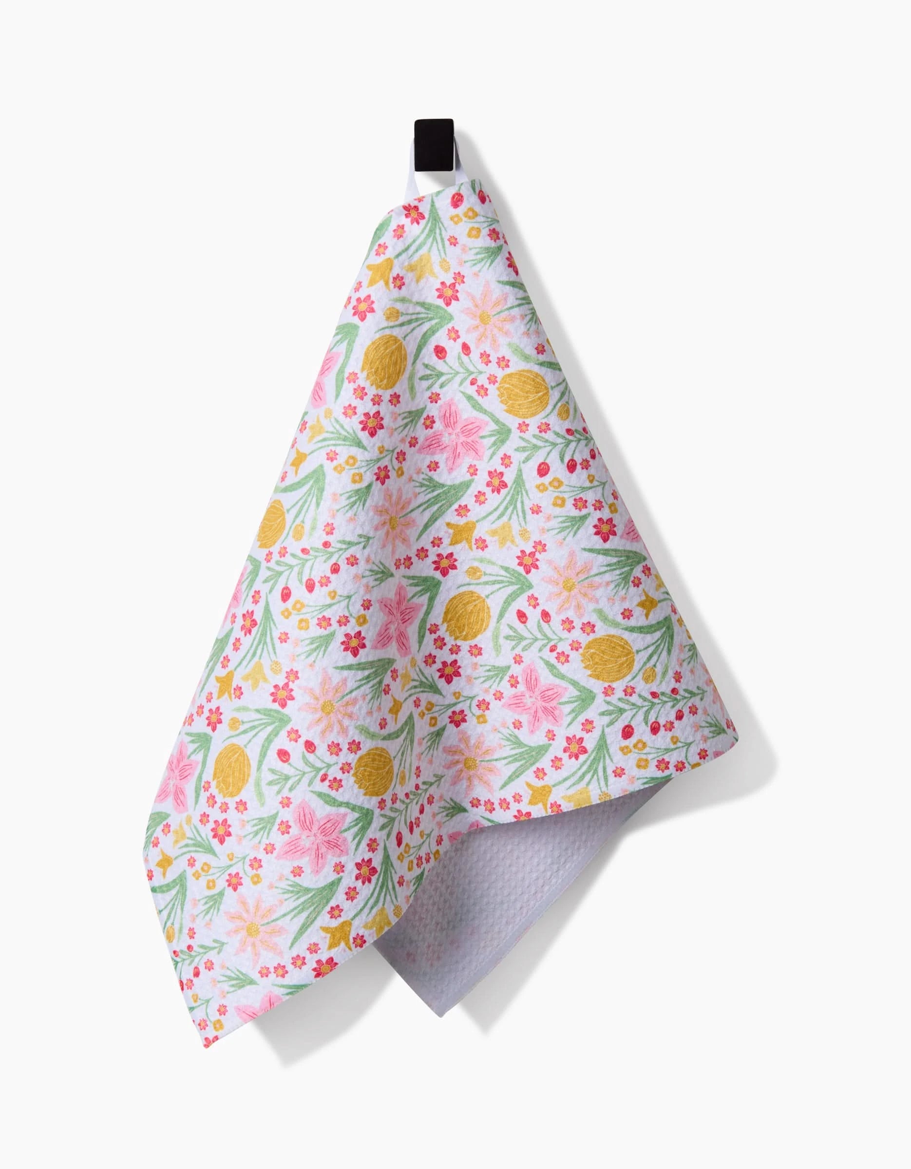 The Danelys Sidron Garden of Light bar towel, featuring a pink, green, and yellow floral and lemon pattern, hangs from a black loop against a white background. Crafted with Geoweave fabric for superior absorbency.