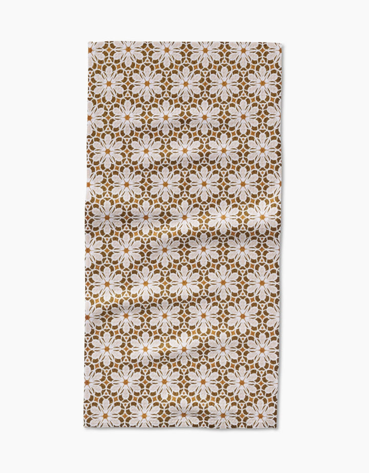 The Geometric Flower cloth by Marta Harvey features a repeating geometric floral pattern in white and brown on Geoweave fabric, shown slightly wrinkled against a plain white background.