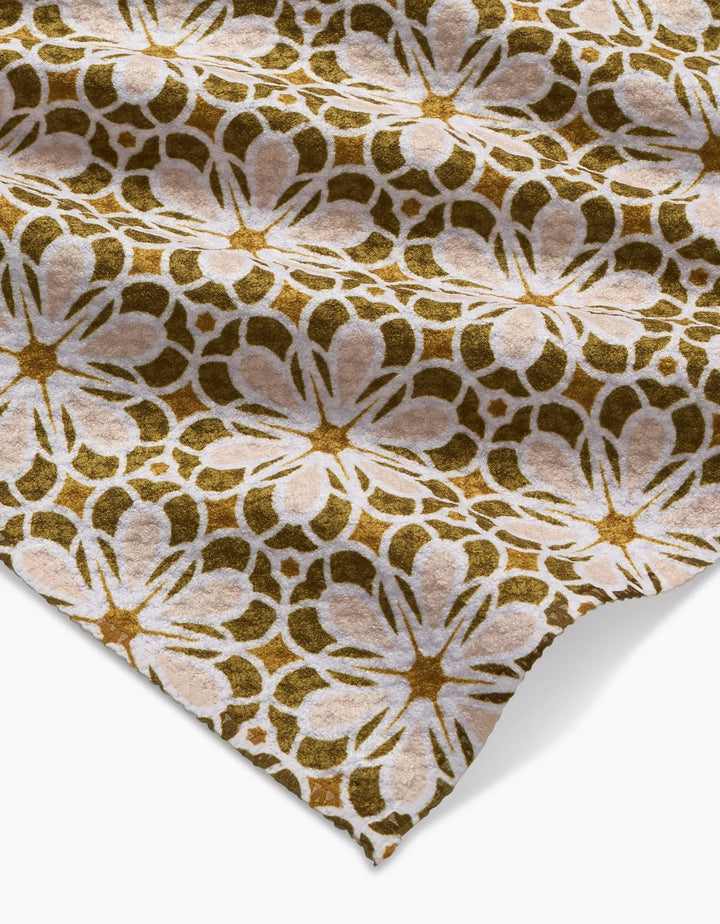 The Marta Harvey Geometric Flower Geoweave bar towel features a brown, tan, and white repeating floral pattern, with visible edges and a softly wrinkled texture against a white background.