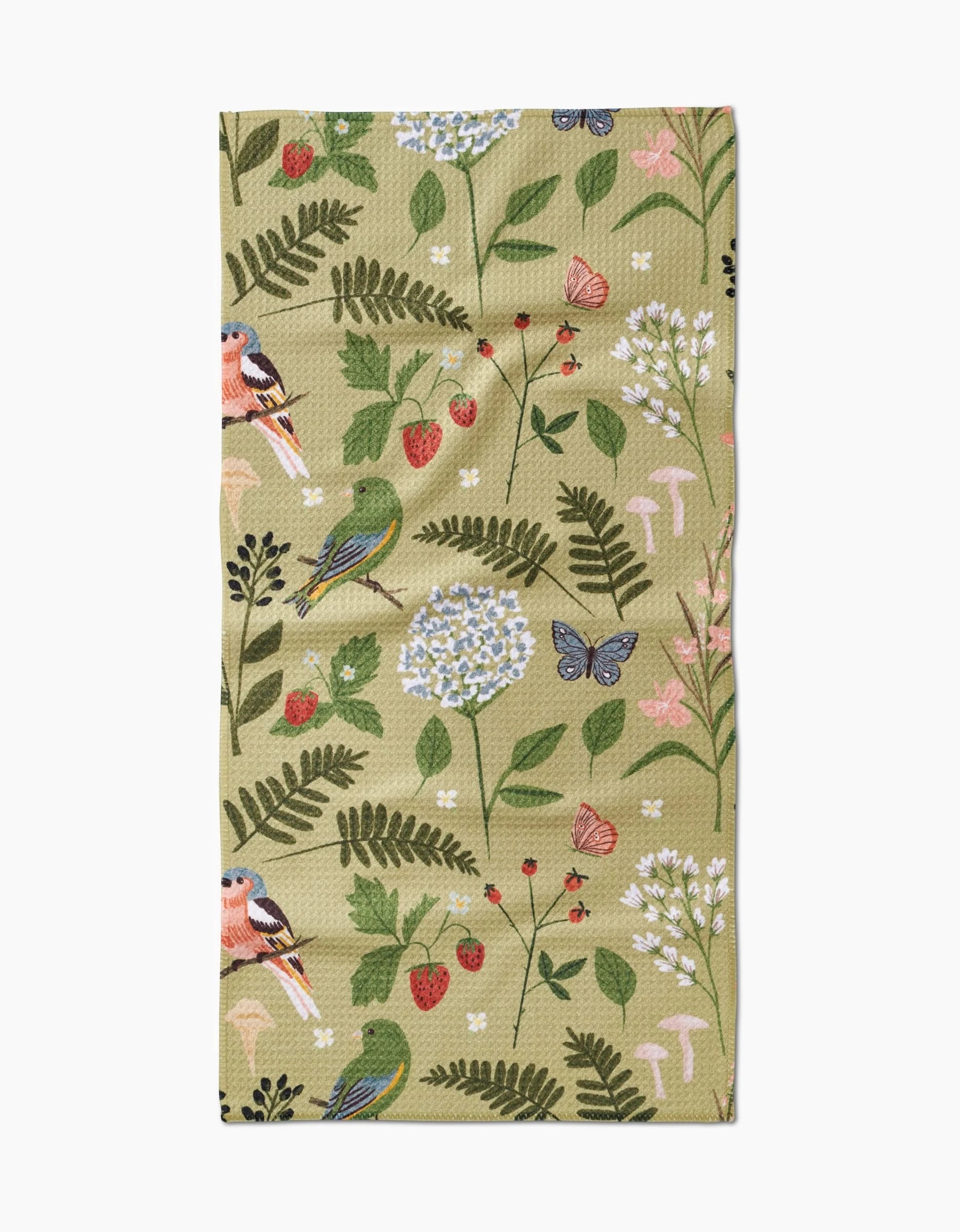 The Good Green Earth bar towel by Janna Sue Design is a beige, recycled cloth featuring a whimsical nature-inspired illustration of birds, butterflies, strawberries, flowers, leaves, and mushrooms in various colors.