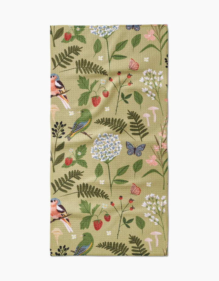 The Good Green Earth bar towel by Janna Sue Design is a beige, recycled cloth featuring a whimsical nature-inspired illustration of birds, butterflies, strawberries, flowers, leaves, and mushrooms in various colors.