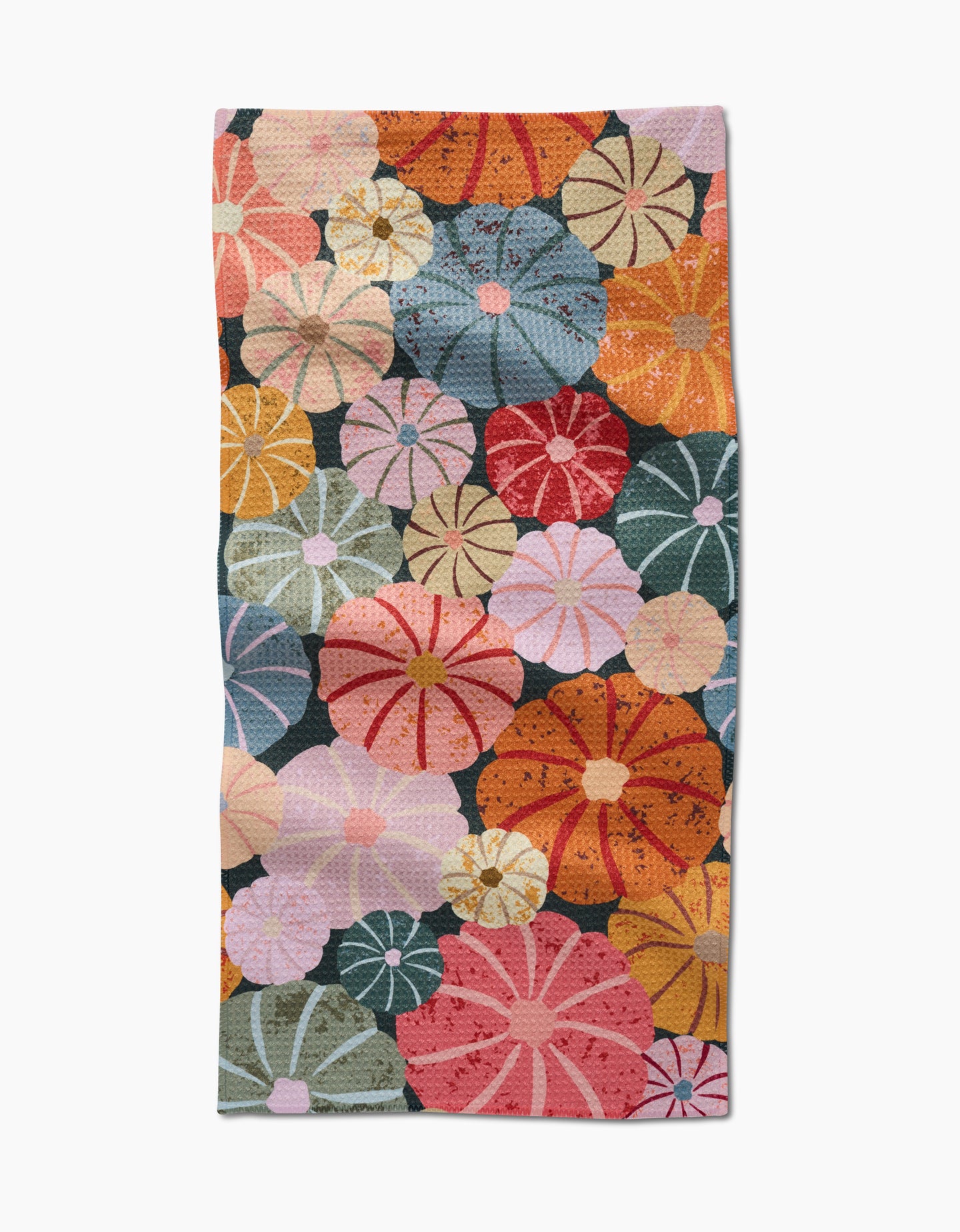 The Gorgeous Gourds towel by Rebecca Bobko is ultra-absorbent and features a vibrant pattern of overlapping, stylized flowers in orange, red, pink, yellow, blue, and green on a dark background.